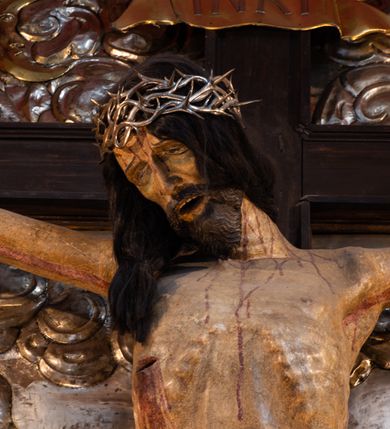 Zdjęcie nr 7: Ołtarz architektoniczny, trójosiowy, dwukondygnacyjny ze zwieńczeniem. Mensa prostopadłościenna, kamienna z drewnianym antepedium w formie leżącego prostokąta z postacią św. Augustyna ujętego wicią suchego akantu z przeplecioną, karbowaną wstążką i bukietami kwiatów. Przedstawienie otoczone profilowaną, ażurową ramą wypełnioną podobną wicią z akantu i kwiatów. Na mensie prostopadłościenne tabernakulum w formie kapliczki. Ściana frontowa z drzwiczkami w kształcie stojącego prostokąta dekorowanego krzyżem łacińskim ujętym wicią roślinną, zwieńczona trójkątnym przyczółkiem. Ścianka ujęta lizenami wypełnionymi wicią akantową podtrzymującymi pełne belkowanie obiegające bryłę, z mocno wysuniętym gzymsem wyłamanym w narożach. Całość zwieńczona czterospadowym dachem dekorowanym łuską. Na dachu baranek Boży leżący na księdze z siedmioma pieczęciami, przytrzymujący chorągiew, ukazany na tle chrystogramu otoczonego glorią promienistą. 
Nastawa na dwudzielnym cokole z półkolistymi bramkami ze zwieńczeniem utworzonym z ornamentu okuciowego ujmującego owalne pola. Osie pierwszej kondygnacji wydzielone kolumnami stojącymi na konsolach dekorowanych z frontu uskrzydlonymi główkami anielskimi powyżej liści akantu, na krawędziach cekinami, a po bokach wicią. Kolumny zostały przedzielone opaską w jednej trzeciej wysokości, dekorowane na całej wysokości wicią roślinną, główkami anielskimi w dolnej partii i imitacją kameryzacji na opaskach oraz w dwóch trzecich wysokości. Kolumny są ustawione na tle pilastrów dekorowanych wicią roślinną i zawieszonymi na niej chustkami. W polu centralnym kondygnacji jest nisza w kształcie stojącego prostokąta zamkniętego łukiem pełnym z postacią ukrzyżowanego Chrystusa na tle widoku Jerozolimy. W osiach bocznych mniejsze, ujęte pilastrami nisze o podobnym kształcie, których konchy wypełnione są muszlą, zwieńczone trójkątnym przyczółkiem przerwanym na cokół. W nich, na dekorowanych wicią i rozetami konsolach ustawiono figury: po lewej stronie św. Piotra, a po prawej św. Pawła. Kondygnacje ujmują ażurowe uszaki utworzone z ornamentu okuciowego, ulistnionych wolut i przewieszonej chustki. Kolumny podtrzymują pełne belkowanie wyniesione w łuk nad polem centralnym. Podłucze dekorowane rozetami, fryz głowami anielskimi i wicią, gzyms m.in. kostkowaniem i liśćmi akantu. Całość spięta kluczem z kartuszem z herbem kanoników regularnych od pokuty (marków). Na wyniesieniu belkowania posadowiono postaci aniołów trzymających narzędzia męki: anioł po lewej włócznię, a anioł po prawej gąbkę. Górna kondygnacja oparta została na schemacie aediculi – prostokątne pole ujęto kolumnami podtrzymującymi pełne belkowanie i trójkątny przyczółek przerwany na środku na cokół, na którym ustawiono rzeźbę  pelikana karmiącego młode własną krwią. Na krawędziach przyczółka dwie leżące postaci. Kondygnacja flankowana postaciami czterech ewangelistów ustawionymi na cokołach. Po lewej stronie św. Marek i św. Jan, po prawej św. Mateusz i św. Łukasz. Struktura polichromowana na kolor ciemnoniebieski; kolumny, profile, detale i ornamenty złocone i srebrzone.
