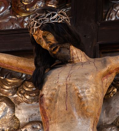 Zdjęcie nr 5: Ołtarz architektoniczny, trójosiowy, dwukondygnacyjny ze zwieńczeniem. Mensa prostopadłościenna, kamienna z drewnianym antepedium w formie leżącego prostokąta z postacią św. Augustyna ujętego wicią suchego akantu z przeplecioną, karbowaną wstążką i bukietami kwiatów. Przedstawienie otoczone profilowaną, ażurową ramą wypełnioną podobną wicią z akantu i kwiatów. Na mensie prostopadłościenne tabernakulum w formie kapliczki. Ściana frontowa z drzwiczkami w kształcie stojącego prostokąta dekorowanego krzyżem łacińskim ujętym wicią roślinną, zwieńczona trójkątnym przyczółkiem. Ścianka ujęta lizenami wypełnionymi wicią akantową podtrzymującymi pełne belkowanie obiegające bryłę, z mocno wysuniętym gzymsem wyłamanym w narożach. Całość zwieńczona czterospadowym dachem dekorowanym łuską. Na dachu baranek Boży leżący na księdze z siedmioma pieczęciami, przytrzymujący chorągiew, ukazany na tle chrystogramu otoczonego glorią promienistą. 
Nastawa na dwudzielnym cokole z półkolistymi bramkami ze zwieńczeniem utworzonym z ornamentu okuciowego ujmującego owalne pola. Osie pierwszej kondygnacji wydzielone kolumnami stojącymi na konsolach dekorowanych z frontu uskrzydlonymi główkami anielskimi powyżej liści akantu, na krawędziach cekinami, a po bokach wicią. Kolumny zostały przedzielone opaską w jednej trzeciej wysokości, dekorowane na całej wysokości wicią roślinną, główkami anielskimi w dolnej partii i imitacją kameryzacji na opaskach oraz w dwóch trzecich wysokości. Kolumny są ustawione na tle pilastrów dekorowanych wicią roślinną i zawieszonymi na niej chustkami. W polu centralnym kondygnacji jest nisza w kształcie stojącego prostokąta zamkniętego łukiem pełnym z postacią ukrzyżowanego Chrystusa na tle widoku Jerozolimy. W osiach bocznych mniejsze, ujęte pilastrami nisze o podobnym kształcie, których konchy wypełnione są muszlą, zwieńczone trójkątnym przyczółkiem przerwanym na cokół. W nich, na dekorowanych wicią i rozetami konsolach ustawiono figury: po lewej stronie św. Piotra, a po prawej św. Pawła. Kondygnacje ujmują ażurowe uszaki utworzone z ornamentu okuciowego, ulistnionych wolut i przewieszonej chustki. Kolumny podtrzymują pełne belkowanie wyniesione w łuk nad polem centralnym. Podłucze dekorowane rozetami, fryz głowami anielskimi i wicią, gzyms m.in. kostkowaniem i liśćmi akantu. Całość spięta kluczem z kartuszem z herbem kanoników regularnych od pokuty (marków). Na wyniesieniu belkowania posadowiono postaci aniołów trzymających narzędzia męki: anioł po lewej włócznię, a anioł po prawej gąbkę. Górna kondygnacja oparta została na schemacie aediculi – prostokątne pole ujęto kolumnami podtrzymującymi pełne belkowanie i trójkątny przyczółek przerwany na środku na cokół, na którym ustawiono rzeźbę  pelikana karmiącego młode własną krwią. Na krawędziach przyczółka dwie leżące postaci. Kondygnacja flankowana postaciami czterech ewangelistów ustawionymi na cokołach. Po lewej stronie św. Marek i św. Jan, po prawej św. Mateusz i św. Łukasz. Struktura polichromowana na kolor ciemnoniebieski; kolumny, profile, detale i ornamenty złocone i srebrzone.
