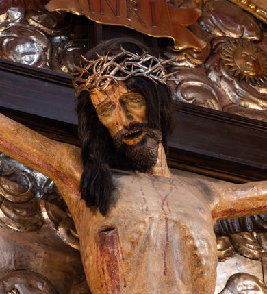 Zdjęcie nr 8: Ołtarz architektoniczny, trójosiowy, dwukondygnacyjny ze zwieńczeniem. Mensa prostopadłościenna, kamienna z drewnianym antepedium w formie leżącego prostokąta z postacią św. Augustyna ujętego wicią suchego akantu z przeplecioną, karbowaną wstążką i bukietami kwiatów. Przedstawienie otoczone profilowaną, ażurową ramą wypełnioną podobną wicią z akantu i kwiatów. Na mensie prostopadłościenne tabernakulum w formie kapliczki. Ściana frontowa z drzwiczkami w kształcie stojącego prostokąta dekorowanego krzyżem łacińskim ujętym wicią roślinną, zwieńczona trójkątnym przyczółkiem. Ścianka ujęta lizenami wypełnionymi wicią akantową podtrzymującymi pełne belkowanie obiegające bryłę, z mocno wysuniętym gzymsem wyłamanym w narożach. Całość zwieńczona czterospadowym dachem dekorowanym łuską. Na dachu baranek Boży leżący na księdze z siedmioma pieczęciami, przytrzymujący chorągiew, ukazany na tle chrystogramu otoczonego glorią promienistą. 
Nastawa na dwudzielnym cokole z półkolistymi bramkami ze zwieńczeniem utworzonym z ornamentu okuciowego ujmującego owalne pola. Osie pierwszej kondygnacji wydzielone kolumnami stojącymi na konsolach dekorowanych z frontu uskrzydlonymi główkami anielskimi powyżej liści akantu, na krawędziach cekinami, a po bokach wicią. Kolumny zostały przedzielone opaską w jednej trzeciej wysokości, dekorowane na całej wysokości wicią roślinną, główkami anielskimi w dolnej partii i imitacją kameryzacji na opaskach oraz w dwóch trzecich wysokości. Kolumny są ustawione na tle pilastrów dekorowanych wicią roślinną i zawieszonymi na niej chustkami. W polu centralnym kondygnacji jest nisza w kształcie stojącego prostokąta zamkniętego łukiem pełnym z postacią ukrzyżowanego Chrystusa na tle widoku Jerozolimy. W osiach bocznych mniejsze, ujęte pilastrami nisze o podobnym kształcie, których konchy wypełnione są muszlą, zwieńczone trójkątnym przyczółkiem przerwanym na cokół. W nich, na dekorowanych wicią i rozetami konsolach ustawiono figury: po lewej stronie św. Piotra, a po prawej św. Pawła. Kondygnacje ujmują ażurowe uszaki utworzone z ornamentu okuciowego, ulistnionych wolut i przewieszonej chustki. Kolumny podtrzymują pełne belkowanie wyniesione w łuk nad polem centralnym. Podłucze dekorowane rozetami, fryz głowami anielskimi i wicią, gzyms m.in. kostkowaniem i liśćmi akantu. Całość spięta kluczem z kartuszem z herbem kanoników regularnych od pokuty (marków). Na wyniesieniu belkowania posadowiono postaci aniołów trzymających narzędzia męki: anioł po lewej włócznię, a anioł po prawej gąbkę. Górna kondygnacja oparta została na schemacie aediculi – prostokątne pole ujęto kolumnami podtrzymującymi pełne belkowanie i trójkątny przyczółek przerwany na środku na cokół, na którym ustawiono rzeźbę  pelikana karmiącego młode własną krwią. Na krawędziach przyczółka dwie leżące postaci. Kondygnacja flankowana postaciami czterech ewangelistów ustawionymi na cokołach. Po lewej stronie św. Marek i św. Jan, po prawej św. Mateusz i św. Łukasz. Struktura polichromowana na kolor ciemnoniebieski; kolumny, profile, detale i ornamenty złocone i srebrzone.
