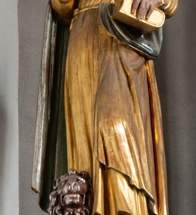 Zdjęcie nr 27: Ołtarz architektoniczny, trójosiowy, dwukondygnacyjny ze zwieńczeniem. Mensa prostopadłościenna, kamienna z drewnianym antepedium w formie leżącego prostokąta z postacią św. Augustyna ujętego wicią suchego akantu z przeplecioną, karbowaną wstążką i bukietami kwiatów. Przedstawienie otoczone profilowaną, ażurową ramą wypełnioną podobną wicią z akantu i kwiatów. Na mensie prostopadłościenne tabernakulum w formie kapliczki. Ściana frontowa z drzwiczkami w kształcie stojącego prostokąta dekorowanego krzyżem łacińskim ujętym wicią roślinną, zwieńczona trójkątnym przyczółkiem. Ścianka ujęta lizenami wypełnionymi wicią akantową podtrzymującymi pełne belkowanie obiegające bryłę, z mocno wysuniętym gzymsem wyłamanym w narożach. Całość zwieńczona czterospadowym dachem dekorowanym łuską. Na dachu baranek Boży leżący na księdze z siedmioma pieczęciami, przytrzymujący chorągiew, ukazany na tle chrystogramu otoczonego glorią promienistą. 
Nastawa na dwudzielnym cokole z półkolistymi bramkami ze zwieńczeniem utworzonym z ornamentu okuciowego ujmującego owalne pola. Osie pierwszej kondygnacji wydzielone kolumnami stojącymi na konsolach dekorowanych z frontu uskrzydlonymi główkami anielskimi powyżej liści akantu, na krawędziach cekinami, a po bokach wicią. Kolumny zostały przedzielone opaską w jednej trzeciej wysokości, dekorowane na całej wysokości wicią roślinną, główkami anielskimi w dolnej partii i imitacją kameryzacji na opaskach oraz w dwóch trzecich wysokości. Kolumny są ustawione na tle pilastrów dekorowanych wicią roślinną i zawieszonymi na niej chustkami. W polu centralnym kondygnacji jest nisza w kształcie stojącego prostokąta zamkniętego łukiem pełnym z postacią ukrzyżowanego Chrystusa na tle widoku Jerozolimy. W osiach bocznych mniejsze, ujęte pilastrami nisze o podobnym kształcie, których konchy wypełnione są muszlą, zwieńczone trójkątnym przyczółkiem przerwanym na cokół. W nich, na dekorowanych wicią i rozetami konsolach ustawiono figury: po lewej stronie św. Piotra, a po prawej św. Pawła. Kondygnacje ujmują ażurowe uszaki utworzone z ornamentu okuciowego, ulistnionych wolut i przewieszonej chustki. Kolumny podtrzymują pełne belkowanie wyniesione w łuk nad polem centralnym. Podłucze dekorowane rozetami, fryz głowami anielskimi i wicią, gzyms m.in. kostkowaniem i liśćmi akantu. Całość spięta kluczem z kartuszem z herbem kanoników regularnych od pokuty (marków). Na wyniesieniu belkowania posadowiono postaci aniołów trzymających narzędzia męki: anioł po lewej włócznię, a anioł po prawej gąbkę. Górna kondygnacja oparta została na schemacie aediculi – prostokątne pole ujęto kolumnami podtrzymującymi pełne belkowanie i trójkątny przyczółek przerwany na środku na cokół, na którym ustawiono rzeźbę  pelikana karmiącego młode własną krwią. Na krawędziach przyczółka dwie leżące postaci. Kondygnacja flankowana postaciami czterech ewangelistów ustawionymi na cokołach. Po lewej stronie św. Marek i św. Jan, po prawej św. Mateusz i św. Łukasz. Struktura polichromowana na kolor ciemnoniebieski; kolumny, profile, detale i ornamenty złocone i srebrzone.
