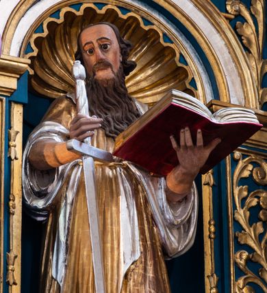 Zdjęcie nr 24: Ołtarz architektoniczny, trójosiowy, dwukondygnacyjny ze zwieńczeniem. Mensa prostopadłościenna, kamienna z drewnianym antepedium w formie leżącego prostokąta z postacią św. Augustyna ujętego wicią suchego akantu z przeplecioną, karbowaną wstążką i bukietami kwiatów. Przedstawienie otoczone profilowaną, ażurową ramą wypełnioną podobną wicią z akantu i kwiatów. Na mensie prostopadłościenne tabernakulum w formie kapliczki. Ściana frontowa z drzwiczkami w kształcie stojącego prostokąta dekorowanego krzyżem łacińskim ujętym wicią roślinną, zwieńczona trójkątnym przyczółkiem. Ścianka ujęta lizenami wypełnionymi wicią akantową podtrzymującymi pełne belkowanie obiegające bryłę, z mocno wysuniętym gzymsem wyłamanym w narożach. Całość zwieńczona czterospadowym dachem dekorowanym łuską. Na dachu baranek Boży leżący na księdze z siedmioma pieczęciami, przytrzymujący chorągiew, ukazany na tle chrystogramu otoczonego glorią promienistą. 
Nastawa na dwudzielnym cokole z półkolistymi bramkami ze zwieńczeniem utworzonym z ornamentu okuciowego ujmującego owalne pola. Osie pierwszej kondygnacji wydzielone kolumnami stojącymi na konsolach dekorowanych z frontu uskrzydlonymi główkami anielskimi powyżej liści akantu, na krawędziach cekinami, a po bokach wicią. Kolumny zostały przedzielone opaską w jednej trzeciej wysokości, dekorowane na całej wysokości wicią roślinną, główkami anielskimi w dolnej partii i imitacją kameryzacji na opaskach oraz w dwóch trzecich wysokości. Kolumny są ustawione na tle pilastrów dekorowanych wicią roślinną i zawieszonymi na niej chustkami. W polu centralnym kondygnacji jest nisza w kształcie stojącego prostokąta zamkniętego łukiem pełnym z postacią ukrzyżowanego Chrystusa na tle widoku Jerozolimy. W osiach bocznych mniejsze, ujęte pilastrami nisze o podobnym kształcie, których konchy wypełnione są muszlą, zwieńczone trójkątnym przyczółkiem przerwanym na cokół. W nich, na dekorowanych wicią i rozetami konsolach ustawiono figury: po lewej stronie św. Piotra, a po prawej św. Pawła. Kondygnacje ujmują ażurowe uszaki utworzone z ornamentu okuciowego, ulistnionych wolut i przewieszonej chustki. Kolumny podtrzymują pełne belkowanie wyniesione w łuk nad polem centralnym. Podłucze dekorowane rozetami, fryz głowami anielskimi i wicią, gzyms m.in. kostkowaniem i liśćmi akantu. Całość spięta kluczem z kartuszem z herbem kanoników regularnych od pokuty (marków). Na wyniesieniu belkowania posadowiono postaci aniołów trzymających narzędzia męki: anioł po lewej włócznię, a anioł po prawej gąbkę. Górna kondygnacja oparta została na schemacie aediculi – prostokątne pole ujęto kolumnami podtrzymującymi pełne belkowanie i trójkątny przyczółek przerwany na środku na cokół, na którym ustawiono rzeźbę  pelikana karmiącego młode własną krwią. Na krawędziach przyczółka dwie leżące postaci. Kondygnacja flankowana postaciami czterech ewangelistów ustawionymi na cokołach. Po lewej stronie św. Marek i św. Jan, po prawej św. Mateusz i św. Łukasz. Struktura polichromowana na kolor ciemnoniebieski; kolumny, profile, detale i ornamenty złocone i srebrzone.
