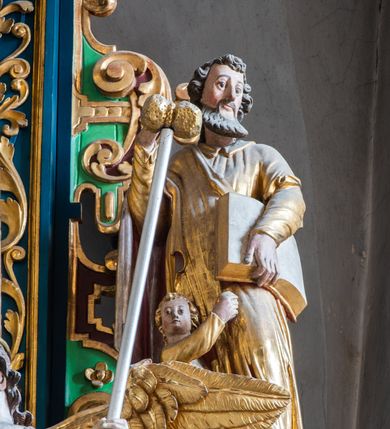 Zdjęcie nr 29: Ołtarz architektoniczny, trójosiowy, dwukondygnacyjny ze zwieńczeniem. Mensa prostopadłościenna, kamienna z drewnianym antepedium w formie leżącego prostokąta z postacią św. Augustyna ujętego wicią suchego akantu z przeplecioną, karbowaną wstążką i bukietami kwiatów. Przedstawienie otoczone profilowaną, ażurową ramą wypełnioną podobną wicią z akantu i kwiatów. Na mensie prostopadłościenne tabernakulum w formie kapliczki. Ściana frontowa z drzwiczkami w kształcie stojącego prostokąta dekorowanego krzyżem łacińskim ujętym wicią roślinną, zwieńczona trójkątnym przyczółkiem. Ścianka ujęta lizenami wypełnionymi wicią akantową podtrzymującymi pełne belkowanie obiegające bryłę, z mocno wysuniętym gzymsem wyłamanym w narożach. Całość zwieńczona czterospadowym dachem dekorowanym łuską. Na dachu baranek Boży leżący na księdze z siedmioma pieczęciami, przytrzymujący chorągiew, ukazany na tle chrystogramu otoczonego glorią promienistą. 
Nastawa na dwudzielnym cokole z półkolistymi bramkami ze zwieńczeniem utworzonym z ornamentu okuciowego ujmującego owalne pola. Osie pierwszej kondygnacji wydzielone kolumnami stojącymi na konsolach dekorowanych z frontu uskrzydlonymi główkami anielskimi powyżej liści akantu, na krawędziach cekinami, a po bokach wicią. Kolumny zostały przedzielone opaską w jednej trzeciej wysokości, dekorowane na całej wysokości wicią roślinną, główkami anielskimi w dolnej partii i imitacją kameryzacji na opaskach oraz w dwóch trzecich wysokości. Kolumny są ustawione na tle pilastrów dekorowanych wicią roślinną i zawieszonymi na niej chustkami. W polu centralnym kondygnacji jest nisza w kształcie stojącego prostokąta zamkniętego łukiem pełnym z postacią ukrzyżowanego Chrystusa na tle widoku Jerozolimy. W osiach bocznych mniejsze, ujęte pilastrami nisze o podobnym kształcie, których konchy wypełnione są muszlą, zwieńczone trójkątnym przyczółkiem przerwanym na cokół. W nich, na dekorowanych wicią i rozetami konsolach ustawiono figury: po lewej stronie św. Piotra, a po prawej św. Pawła. Kondygnacje ujmują ażurowe uszaki utworzone z ornamentu okuciowego, ulistnionych wolut i przewieszonej chustki. Kolumny podtrzymują pełne belkowanie wyniesione w łuk nad polem centralnym. Podłucze dekorowane rozetami, fryz głowami anielskimi i wicią, gzyms m.in. kostkowaniem i liśćmi akantu. Całość spięta kluczem z kartuszem z herbem kanoników regularnych od pokuty (marków). Na wyniesieniu belkowania posadowiono postaci aniołów trzymających narzędzia męki: anioł po lewej włócznię, a anioł po prawej gąbkę. Górna kondygnacja oparta została na schemacie aediculi – prostokątne pole ujęto kolumnami podtrzymującymi pełne belkowanie i trójkątny przyczółek przerwany na środku na cokół, na którym ustawiono rzeźbę  pelikana karmiącego młode własną krwią. Na krawędziach przyczółka dwie leżące postaci. Kondygnacja flankowana postaciami czterech ewangelistów ustawionymi na cokołach. Po lewej stronie św. Marek i św. Jan, po prawej św. Mateusz i św. Łukasz. Struktura polichromowana na kolor ciemnoniebieski; kolumny, profile, detale i ornamenty złocone i srebrzone.
