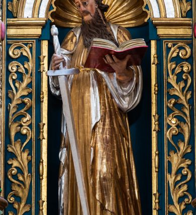 Zdjęcie nr 30: Ołtarz architektoniczny, trójosiowy, dwukondygnacyjny ze zwieńczeniem. Mensa prostopadłościenna, kamienna z drewnianym antepedium w formie leżącego prostokąta z postacią św. Augustyna ujętego wicią suchego akantu z przeplecioną, karbowaną wstążką i bukietami kwiatów. Przedstawienie otoczone profilowaną, ażurową ramą wypełnioną podobną wicią z akantu i kwiatów. Na mensie prostopadłościenne tabernakulum w formie kapliczki. Ściana frontowa z drzwiczkami w kształcie stojącego prostokąta dekorowanego krzyżem łacińskim ujętym wicią roślinną, zwieńczona trójkątnym przyczółkiem. Ścianka ujęta lizenami wypełnionymi wicią akantową podtrzymującymi pełne belkowanie obiegające bryłę, z mocno wysuniętym gzymsem wyłamanym w narożach. Całość zwieńczona czterospadowym dachem dekorowanym łuską. Na dachu baranek Boży leżący na księdze z siedmioma pieczęciami, przytrzymujący chorągiew, ukazany na tle chrystogramu otoczonego glorią promienistą. 
Nastawa na dwudzielnym cokole z półkolistymi bramkami ze zwieńczeniem utworzonym z ornamentu okuciowego ujmującego owalne pola. Osie pierwszej kondygnacji wydzielone kolumnami stojącymi na konsolach dekorowanych z frontu uskrzydlonymi główkami anielskimi powyżej liści akantu, na krawędziach cekinami, a po bokach wicią. Kolumny zostały przedzielone opaską w jednej trzeciej wysokości, dekorowane na całej wysokości wicią roślinną, główkami anielskimi w dolnej partii i imitacją kameryzacji na opaskach oraz w dwóch trzecich wysokości. Kolumny są ustawione na tle pilastrów dekorowanych wicią roślinną i zawieszonymi na niej chustkami. W polu centralnym kondygnacji jest nisza w kształcie stojącego prostokąta zamkniętego łukiem pełnym z postacią ukrzyżowanego Chrystusa na tle widoku Jerozolimy. W osiach bocznych mniejsze, ujęte pilastrami nisze o podobnym kształcie, których konchy wypełnione są muszlą, zwieńczone trójkątnym przyczółkiem przerwanym na cokół. W nich, na dekorowanych wicią i rozetami konsolach ustawiono figury: po lewej stronie św. Piotra, a po prawej św. Pawła. Kondygnacje ujmują ażurowe uszaki utworzone z ornamentu okuciowego, ulistnionych wolut i przewieszonej chustki. Kolumny podtrzymują pełne belkowanie wyniesione w łuk nad polem centralnym. Podłucze dekorowane rozetami, fryz głowami anielskimi i wicią, gzyms m.in. kostkowaniem i liśćmi akantu. Całość spięta kluczem z kartuszem z herbem kanoników regularnych od pokuty (marków). Na wyniesieniu belkowania posadowiono postaci aniołów trzymających narzędzia męki: anioł po lewej włócznię, a anioł po prawej gąbkę. Górna kondygnacja oparta została na schemacie aediculi – prostokątne pole ujęto kolumnami podtrzymującymi pełne belkowanie i trójkątny przyczółek przerwany na środku na cokół, na którym ustawiono rzeźbę  pelikana karmiącego młode własną krwią. Na krawędziach przyczółka dwie leżące postaci. Kondygnacja flankowana postaciami czterech ewangelistów ustawionymi na cokołach. Po lewej stronie św. Marek i św. Jan, po prawej św. Mateusz i św. Łukasz. Struktura polichromowana na kolor ciemnoniebieski; kolumny, profile, detale i ornamenty złocone i srebrzone.
