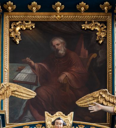 Zdjęcie nr 63: Ołtarz architektoniczny, trójosiowy, dwukondygnacyjny ze zwieńczeniem. Mensa prostopadłościenna, kamienna z drewnianym antepedium w formie leżącego prostokąta z postacią św. Augustyna ujętego wicią suchego akantu z przeplecioną, karbowaną wstążką i bukietami kwiatów. Przedstawienie otoczone profilowaną, ażurową ramą wypełnioną podobną wicią z akantu i kwiatów. Na mensie prostopadłościenne tabernakulum w formie kapliczki. Ściana frontowa z drzwiczkami w kształcie stojącego prostokąta dekorowanego krzyżem łacińskim ujętym wicią roślinną, zwieńczona trójkątnym przyczółkiem. Ścianka ujęta lizenami wypełnionymi wicią akantową podtrzymującymi pełne belkowanie obiegające bryłę, z mocno wysuniętym gzymsem wyłamanym w narożach. Całość zwieńczona czterospadowym dachem dekorowanym łuską. Na dachu baranek Boży leżący na księdze z siedmioma pieczęciami, przytrzymujący chorągiew, ukazany na tle chrystogramu otoczonego glorią promienistą. 
Nastawa na dwudzielnym cokole z półkolistymi bramkami ze zwieńczeniem utworzonym z ornamentu okuciowego ujmującego owalne pola. Osie pierwszej kondygnacji wydzielone kolumnami stojącymi na konsolach dekorowanych z frontu uskrzydlonymi główkami anielskimi powyżej liści akantu, na krawędziach cekinami, a po bokach wicią. Kolumny zostały przedzielone opaską w jednej trzeciej wysokości, dekorowane na całej wysokości wicią roślinną, główkami anielskimi w dolnej partii i imitacją kameryzacji na opaskach oraz w dwóch trzecich wysokości. Kolumny są ustawione na tle pilastrów dekorowanych wicią roślinną i zawieszonymi na niej chustkami. W polu centralnym kondygnacji jest nisza w kształcie stojącego prostokąta zamkniętego łukiem pełnym z postacią ukrzyżowanego Chrystusa na tle widoku Jerozolimy. W osiach bocznych mniejsze, ujęte pilastrami nisze o podobnym kształcie, których konchy wypełnione są muszlą, zwieńczone trójkątnym przyczółkiem przerwanym na cokół. W nich, na dekorowanych wicią i rozetami konsolach ustawiono figury: po lewej stronie św. Piotra, a po prawej św. Pawła. Kondygnacje ujmują ażurowe uszaki utworzone z ornamentu okuciowego, ulistnionych wolut i przewieszonej chustki. Kolumny podtrzymują pełne belkowanie wyniesione w łuk nad polem centralnym. Podłucze dekorowane rozetami, fryz głowami anielskimi i wicią, gzyms m.in. kostkowaniem i liśćmi akantu. Całość spięta kluczem z kartuszem z herbem kanoników regularnych od pokuty (marków). Na wyniesieniu belkowania posadowiono postaci aniołów trzymających narzędzia męki: anioł po lewej włócznię, a anioł po prawej gąbkę. Górna kondygnacja oparta została na schemacie aediculi – prostokątne pole ujęto kolumnami podtrzymującymi pełne belkowanie i trójkątny przyczółek przerwany na środku na cokół, na którym ustawiono rzeźbę  pelikana karmiącego młode własną krwią. Na krawędziach przyczółka dwie leżące postaci. Kondygnacja flankowana postaciami czterech ewangelistów ustawionymi na cokołach. Po lewej stronie św. Marek i św. Jan, po prawej św. Mateusz i św. Łukasz. Struktura polichromowana na kolor ciemnoniebieski; kolumny, profile, detale i ornamenty złocone i srebrzone.
