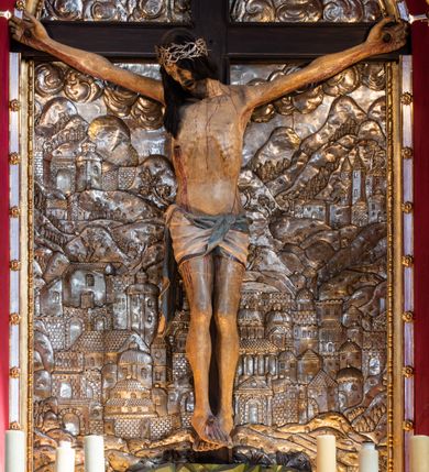 Zdjęcie nr 6: Ołtarz architektoniczny, trójosiowy, dwukondygnacyjny ze zwieńczeniem. Mensa prostopadłościenna, kamienna z drewnianym antepedium w formie leżącego prostokąta z postacią św. Augustyna ujętego wicią suchego akantu z przeplecioną, karbowaną wstążką i bukietami kwiatów. Przedstawienie otoczone profilowaną, ażurową ramą wypełnioną podobną wicią z akantu i kwiatów. Na mensie prostopadłościenne tabernakulum w formie kapliczki. Ściana frontowa z drzwiczkami w kształcie stojącego prostokąta dekorowanego krzyżem łacińskim ujętym wicią roślinną, zwieńczona trójkątnym przyczółkiem. Ścianka ujęta lizenami wypełnionymi wicią akantową podtrzymującymi pełne belkowanie obiegające bryłę, z mocno wysuniętym gzymsem wyłamanym w narożach. Całość zwieńczona czterospadowym dachem dekorowanym łuską. Na dachu baranek Boży leżący na księdze z siedmioma pieczęciami, przytrzymujący chorągiew, ukazany na tle chrystogramu otoczonego glorią promienistą. 
Nastawa na dwudzielnym cokole z półkolistymi bramkami ze zwieńczeniem utworzonym z ornamentu okuciowego ujmującego owalne pola. Osie pierwszej kondygnacji wydzielone kolumnami stojącymi na konsolach dekorowanych z frontu uskrzydlonymi główkami anielskimi powyżej liści akantu, na krawędziach cekinami, a po bokach wicią. Kolumny zostały przedzielone opaską w jednej trzeciej wysokości, dekorowane na całej wysokości wicią roślinną, główkami anielskimi w dolnej partii i imitacją kameryzacji na opaskach oraz w dwóch trzecich wysokości. Kolumny są ustawione na tle pilastrów dekorowanych wicią roślinną i zawieszonymi na niej chustkami. W polu centralnym kondygnacji jest nisza w kształcie stojącego prostokąta zamkniętego łukiem pełnym z postacią ukrzyżowanego Chrystusa na tle widoku Jerozolimy. W osiach bocznych mniejsze, ujęte pilastrami nisze o podobnym kształcie, których konchy wypełnione są muszlą, zwieńczone trójkątnym przyczółkiem przerwanym na cokół. W nich, na dekorowanych wicią i rozetami konsolach ustawiono figury: po lewej stronie św. Piotra, a po prawej św. Pawła. Kondygnacje ujmują ażurowe uszaki utworzone z ornamentu okuciowego, ulistnionych wolut i przewieszonej chustki. Kolumny podtrzymują pełne belkowanie wyniesione w łuk nad polem centralnym. Podłucze dekorowane rozetami, fryz głowami anielskimi i wicią, gzyms m.in. kostkowaniem i liśćmi akantu. Całość spięta kluczem z kartuszem z herbem kanoników regularnych od pokuty (marków). Na wyniesieniu belkowania posadowiono postaci aniołów trzymających narzędzia męki: anioł po lewej włócznię, a anioł po prawej gąbkę. Górna kondygnacja oparta została na schemacie aediculi – prostokątne pole ujęto kolumnami podtrzymującymi pełne belkowanie i trójkątny przyczółek przerwany na środku na cokół, na którym ustawiono rzeźbę  pelikana karmiącego młode własną krwią. Na krawędziach przyczółka dwie leżące postaci. Kondygnacja flankowana postaciami czterech ewangelistów ustawionymi na cokołach. Po lewej stronie św. Marek i św. Jan, po prawej św. Mateusz i św. Łukasz. Struktura polichromowana na kolor ciemnoniebieski; kolumny, profile, detale i ornamenty złocone i srebrzone.
