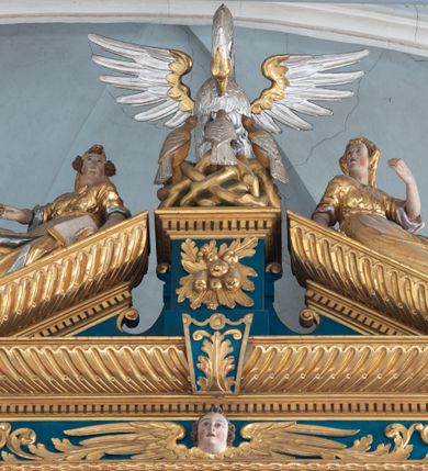 Zdjęcie nr 52: Ołtarz architektoniczny, trójosiowy, dwukondygnacyjny ze zwieńczeniem. Mensa prostopadłościenna, kamienna z drewnianym antepedium w formie leżącego prostokąta z postacią św. Augustyna ujętego wicią suchego akantu z przeplecioną, karbowaną wstążką i bukietami kwiatów. Przedstawienie otoczone profilowaną, ażurową ramą wypełnioną podobną wicią z akantu i kwiatów. Na mensie prostopadłościenne tabernakulum w formie kapliczki. Ściana frontowa z drzwiczkami w kształcie stojącego prostokąta dekorowanego krzyżem łacińskim ujętym wicią roślinną, zwieńczona trójkątnym przyczółkiem. Ścianka ujęta lizenami wypełnionymi wicią akantową podtrzymującymi pełne belkowanie obiegające bryłę, z mocno wysuniętym gzymsem wyłamanym w narożach. Całość zwieńczona czterospadowym dachem dekorowanym łuską. Na dachu baranek Boży leżący na księdze z siedmioma pieczęciami, przytrzymujący chorągiew, ukazany na tle chrystogramu otoczonego glorią promienistą. 
Nastawa na dwudzielnym cokole z półkolistymi bramkami ze zwieńczeniem utworzonym z ornamentu okuciowego ujmującego owalne pola. Osie pierwszej kondygnacji wydzielone kolumnami stojącymi na konsolach dekorowanych z frontu uskrzydlonymi główkami anielskimi powyżej liści akantu, na krawędziach cekinami, a po bokach wicią. Kolumny zostały przedzielone opaską w jednej trzeciej wysokości, dekorowane na całej wysokości wicią roślinną, główkami anielskimi w dolnej partii i imitacją kameryzacji na opaskach oraz w dwóch trzecich wysokości. Kolumny są ustawione na tle pilastrów dekorowanych wicią roślinną i zawieszonymi na niej chustkami. W polu centralnym kondygnacji jest nisza w kształcie stojącego prostokąta zamkniętego łukiem pełnym z postacią ukrzyżowanego Chrystusa na tle widoku Jerozolimy. W osiach bocznych mniejsze, ujęte pilastrami nisze o podobnym kształcie, których konchy wypełnione są muszlą, zwieńczone trójkątnym przyczółkiem przerwanym na cokół. W nich, na dekorowanych wicią i rozetami konsolach ustawiono figury: po lewej stronie św. Piotra, a po prawej św. Pawła. Kondygnacje ujmują ażurowe uszaki utworzone z ornamentu okuciowego, ulistnionych wolut i przewieszonej chustki. Kolumny podtrzymują pełne belkowanie wyniesione w łuk nad polem centralnym. Podłucze dekorowane rozetami, fryz głowami anielskimi i wicią, gzyms m.in. kostkowaniem i liśćmi akantu. Całość spięta kluczem z kartuszem z herbem kanoników regularnych od pokuty (marków). Na wyniesieniu belkowania posadowiono postaci aniołów trzymających narzędzia męki: anioł po lewej włócznię, a anioł po prawej gąbkę. Górna kondygnacja oparta została na schemacie aediculi – prostokątne pole ujęto kolumnami podtrzymującymi pełne belkowanie i trójkątny przyczółek przerwany na środku na cokół, na którym ustawiono rzeźbę  pelikana karmiącego młode własną krwią. Na krawędziach przyczółka dwie leżące postaci. Kondygnacja flankowana postaciami czterech ewangelistów ustawionymi na cokołach. Po lewej stronie św. Marek i św. Jan, po prawej św. Mateusz i św. Łukasz. Struktura polichromowana na kolor ciemnoniebieski; kolumny, profile, detale i ornamenty złocone i srebrzone.
