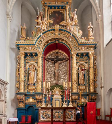 Zdjęcie nr 1: Ołtarz architektoniczny, trójosiowy, dwukondygnacyjny ze zwieńczeniem. Mensa prostopadłościenna, kamienna z drewnianym antepedium w formie leżącego prostokąta z postacią św. Augustyna ujętego wicią suchego akantu z przeplecioną, karbowaną wstążką i bukietami kwiatów. Przedstawienie otoczone profilowaną, ażurową ramą wypełnioną podobną wicią z akantu i kwiatów. Na mensie prostopadłościenne tabernakulum w formie kapliczki. Ściana frontowa z drzwiczkami w kształcie stojącego prostokąta dekorowanego krzyżem łacińskim ujętym wicią roślinną, zwieńczona trójkątnym przyczółkiem. Ścianka ujęta lizenami wypełnionymi wicią akantową podtrzymującymi pełne belkowanie obiegające bryłę, z mocno wysuniętym gzymsem wyłamanym w narożach. Całość zwieńczona czterospadowym dachem dekorowanym łuską. Na dachu baranek Boży leżący na księdze z siedmioma pieczęciami, przytrzymujący chorągiew, ukazany na tle chrystogramu otoczonego glorią promienistą. 
Nastawa na dwudzielnym cokole z półkolistymi bramkami ze zwieńczeniem utworzonym z ornamentu okuciowego ujmującego owalne pola. Osie pierwszej kondygnacji wydzielone kolumnami stojącymi na konsolach dekorowanych z frontu uskrzydlonymi główkami anielskimi powyżej liści akantu, na krawędziach cekinami, a po bokach wicią. Kolumny zostały przedzielone opaską w jednej trzeciej wysokości, dekorowane na całej wysokości wicią roślinną, główkami anielskimi w dolnej partii i imitacją kameryzacji na opaskach oraz w dwóch trzecich wysokości. Kolumny są ustawione na tle pilastrów dekorowanych wicią roślinną i zawieszonymi na niej chustkami. W polu centralnym kondygnacji jest nisza w kształcie stojącego prostokąta zamkniętego łukiem pełnym z postacią ukrzyżowanego Chrystusa na tle widoku Jerozolimy. W osiach bocznych mniejsze, ujęte pilastrami nisze o podobnym kształcie, których konchy wypełnione są muszlą, zwieńczone trójkątnym przyczółkiem przerwanym na cokół. W nich, na dekorowanych wicią i rozetami konsolach ustawiono figury: po lewej stronie św. Piotra, a po prawej św. Pawła. Kondygnacje ujmują ażurowe uszaki utworzone z ornamentu okuciowego, ulistnionych wolut i przewieszonej chustki. Kolumny podtrzymują pełne belkowanie wyniesione w łuk nad polem centralnym. Podłucze dekorowane rozetami, fryz głowami anielskimi i wicią, gzyms m.in. kostkowaniem i liśćmi akantu. Całość spięta kluczem z kartuszem z herbem kanoników regularnych od pokuty (marków). Na wyniesieniu belkowania posadowiono postaci aniołów trzymających narzędzia męki: anioł po lewej włócznię, a anioł po prawej gąbkę. Górna kondygnacja oparta została na schemacie aediculi – prostokątne pole ujęto kolumnami podtrzymującymi pełne belkowanie i trójkątny przyczółek przerwany na środku na cokół, na którym ustawiono rzeźbę  pelikana karmiącego młode własną krwią. Na krawędziach przyczółka dwie leżące postaci. Kondygnacja flankowana postaciami czterech ewangelistów ustawionymi na cokołach. Po lewej stronie św. Marek i św. Jan, po prawej św. Mateusz i św. Łukasz. Struktura polichromowana na kolor ciemnoniebieski; kolumny, profile, detale i ornamenty złocone i srebrzone.
