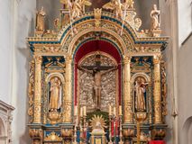 Zdjęcie nr 1: Ołtarz architektoniczny, trójosiowy, dwukondygnacyjny ze zwieńczeniem. Mensa prostopadłościenna, kamienna z drewnianym antepedium w formie leżącego prostokąta z postacią św. Augustyna ujętego wicią suchego akantu z przeplecioną, karbowaną wstążką i bukietami kwiatów. Przedstawienie otoczone profilowaną, ażurową ramą wypełnioną podobną wicią z akantu i kwiatów. Na mensie prostopadłościenne tabernakulum w formie kapliczki. Ściana frontowa z drzwiczkami w kształcie stojącego prostokąta dekorowanego krzyżem łacińskim ujętym wicią roślinną, zwieńczona trójkątnym przyczółkiem. Ścianka ujęta lizenami wypełnionymi wicią akantową podtrzymującymi pełne belkowanie obiegające bryłę, z mocno wysuniętym gzymsem wyłamanym w narożach. Całość zwieńczona czterospadowym dachem dekorowanym łuską. Na dachu baranek Boży leżący na księdze z siedmioma pieczęciami, przytrzymujący chorągiew, ukazany na tle chrystogramu otoczonego glorią promienistą. 
Nastawa na dwudzielnym cokole z półkolistymi bramkami ze zwieńczeniem utworzonym z ornamentu okuciowego ujmującego owalne pola. Osie pierwszej kondygnacji wydzielone kolumnami stojącymi na konsolach dekorowanych z frontu uskrzydlonymi główkami anielskimi powyżej liści akantu, na krawędziach cekinami, a po bokach wicią. Kolumny zostały przedzielone opaską w jednej trzeciej wysokości, dekorowane na całej wysokości wicią roślinną, główkami anielskimi w dolnej partii i imitacją kameryzacji na opaskach oraz w dwóch trzecich wysokości. Kolumny są ustawione na tle pilastrów dekorowanych wicią roślinną i zawieszonymi na niej chustkami. W polu centralnym kondygnacji jest nisza w kształcie stojącego prostokąta zamkniętego łukiem pełnym z postacią ukrzyżowanego Chrystusa na tle widoku Jerozolimy. W osiach bocznych mniejsze, ujęte pilastrami nisze o podobnym kształcie, których konchy wypełnione są muszlą, zwieńczone trójkątnym przyczółkiem przerwanym na cokół. W nich, na dekorowanych wicią i rozetami konsolach ustawiono figury: po lewej stronie św. Piotra, a po prawej św. Pawła. Kondygnacje ujmują ażurowe uszaki utworzone z ornamentu okuciowego, ulistnionych wolut i przewieszonej chustki. Kolumny podtrzymują pełne belkowanie wyniesione w łuk nad polem centralnym. Podłucze dekorowane rozetami, fryz głowami anielskimi i wicią, gzyms m.in. kostkowaniem i liśćmi akantu. Całość spięta kluczem z kartuszem z herbem kanoników regularnych od pokuty (marków). Na wyniesieniu belkowania posadowiono postaci aniołów trzymających narzędzia męki: anioł po lewej włócznię, a anioł po prawej gąbkę. Górna kondygnacja oparta została na schemacie aediculi – prostokątne pole ujęto kolumnami podtrzymującymi pełne belkowanie i trójkątny przyczółek przerwany na środku na cokół, na którym ustawiono rzeźbę  pelikana karmiącego młode własną krwią. Na krawędziach przyczółka dwie leżące postaci. Kondygnacja flankowana postaciami czterech ewangelistów ustawionymi na cokołach. Po lewej stronie św. Marek i św. Jan, po prawej św. Mateusz i św. Łukasz. Struktura polichromowana na kolor ciemnoniebieski; kolumny, profile, detale i ornamenty złocone i srebrzone.
