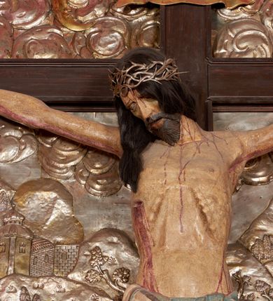 Zdjęcie nr 45: Ołtarz architektoniczny, trójosiowy, dwukondygnacyjny ze zwieńczeniem. Mensa prostopadłościenna, kamienna z drewnianym antepedium w formie leżącego prostokąta z postacią św. Augustyna ujętego wicią suchego akantu z przeplecioną, karbowaną wstążką i bukietami kwiatów. Przedstawienie otoczone profilowaną, ażurową ramą wypełnioną podobną wicią z akantu i kwiatów. Na mensie prostopadłościenne tabernakulum w formie kapliczki. Ściana frontowa z drzwiczkami w kształcie stojącego prostokąta dekorowanego krzyżem łacińskim ujętym wicią roślinną, zwieńczona trójkątnym przyczółkiem. Ścianka ujęta lizenami wypełnionymi wicią akantową podtrzymującymi pełne belkowanie obiegające bryłę, z mocno wysuniętym gzymsem wyłamanym w narożach. Całość zwieńczona czterospadowym dachem dekorowanym łuską. Na dachu baranek Boży leżący na księdze z siedmioma pieczęciami, przytrzymujący chorągiew, ukazany na tle chrystogramu otoczonego glorią promienistą. 
Nastawa na dwudzielnym cokole z półkolistymi bramkami ze zwieńczeniem utworzonym z ornamentu okuciowego ujmującego owalne pola. Osie pierwszej kondygnacji wydzielone kolumnami stojącymi na konsolach dekorowanych z frontu uskrzydlonymi główkami anielskimi powyżej liści akantu, na krawędziach cekinami, a po bokach wicią. Kolumny zostały przedzielone opaską w jednej trzeciej wysokości, dekorowane na całej wysokości wicią roślinną, główkami anielskimi w dolnej partii i imitacją kameryzacji na opaskach oraz w dwóch trzecich wysokości. Kolumny są ustawione na tle pilastrów dekorowanych wicią roślinną i zawieszonymi na niej chustkami. W polu centralnym kondygnacji jest nisza w kształcie stojącego prostokąta zamkniętego łukiem pełnym z postacią ukrzyżowanego Chrystusa na tle widoku Jerozolimy. W osiach bocznych mniejsze, ujęte pilastrami nisze o podobnym kształcie, których konchy wypełnione są muszlą, zwieńczone trójkątnym przyczółkiem przerwanym na cokół. W nich, na dekorowanych wicią i rozetami konsolach ustawiono figury: po lewej stronie św. Piotra, a po prawej św. Pawła. Kondygnacje ujmują ażurowe uszaki utworzone z ornamentu okuciowego, ulistnionych wolut i przewieszonej chustki. Kolumny podtrzymują pełne belkowanie wyniesione w łuk nad polem centralnym. Podłucze dekorowane rozetami, fryz głowami anielskimi i wicią, gzyms m.in. kostkowaniem i liśćmi akantu. Całość spięta kluczem z kartuszem z herbem kanoników regularnych od pokuty (marków). Na wyniesieniu belkowania posadowiono postaci aniołów trzymających narzędzia męki: anioł po lewej włócznię, a anioł po prawej gąbkę. Górna kondygnacja oparta została na schemacie aediculi – prostokątne pole ujęto kolumnami podtrzymującymi pełne belkowanie i trójkątny przyczółek przerwany na środku na cokół, na którym ustawiono rzeźbę  pelikana karmiącego młode własną krwią. Na krawędziach przyczółka dwie leżące postaci. Kondygnacja flankowana postaciami czterech ewangelistów ustawionymi na cokołach. Po lewej stronie św. Marek i św. Jan, po prawej św. Mateusz i św. Łukasz. Struktura polichromowana na kolor ciemnoniebieski; kolumny, profile, detale i ornamenty złocone i srebrzone.
