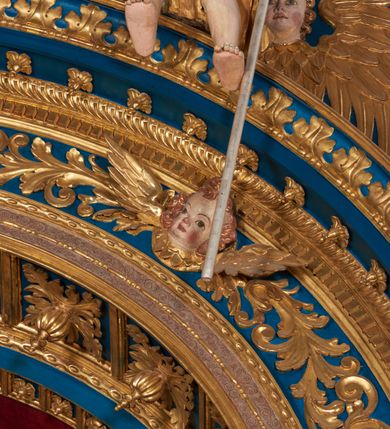 Zdjęcie nr 57: Ołtarz architektoniczny, trójosiowy, dwukondygnacyjny ze zwieńczeniem. Mensa prostopadłościenna, kamienna z drewnianym antepedium w formie leżącego prostokąta z postacią św. Augustyna ujętego wicią suchego akantu z przeplecioną, karbowaną wstążką i bukietami kwiatów. Przedstawienie otoczone profilowaną, ażurową ramą wypełnioną podobną wicią z akantu i kwiatów. Na mensie prostopadłościenne tabernakulum w formie kapliczki. Ściana frontowa z drzwiczkami w kształcie stojącego prostokąta dekorowanego krzyżem łacińskim ujętym wicią roślinną, zwieńczona trójkątnym przyczółkiem. Ścianka ujęta lizenami wypełnionymi wicią akantową podtrzymującymi pełne belkowanie obiegające bryłę, z mocno wysuniętym gzymsem wyłamanym w narożach. Całość zwieńczona czterospadowym dachem dekorowanym łuską. Na dachu baranek Boży leżący na księdze z siedmioma pieczęciami, przytrzymujący chorągiew, ukazany na tle chrystogramu otoczonego glorią promienistą. 
Nastawa na dwudzielnym cokole z półkolistymi bramkami ze zwieńczeniem utworzonym z ornamentu okuciowego ujmującego owalne pola. Osie pierwszej kondygnacji wydzielone kolumnami stojącymi na konsolach dekorowanych z frontu uskrzydlonymi główkami anielskimi powyżej liści akantu, na krawędziach cekinami, a po bokach wicią. Kolumny zostały przedzielone opaską w jednej trzeciej wysokości, dekorowane na całej wysokości wicią roślinną, główkami anielskimi w dolnej partii i imitacją kameryzacji na opaskach oraz w dwóch trzecich wysokości. Kolumny są ustawione na tle pilastrów dekorowanych wicią roślinną i zawieszonymi na niej chustkami. W polu centralnym kondygnacji jest nisza w kształcie stojącego prostokąta zamkniętego łukiem pełnym z postacią ukrzyżowanego Chrystusa na tle widoku Jerozolimy. W osiach bocznych mniejsze, ujęte pilastrami nisze o podobnym kształcie, których konchy wypełnione są muszlą, zwieńczone trójkątnym przyczółkiem przerwanym na cokół. W nich, na dekorowanych wicią i rozetami konsolach ustawiono figury: po lewej stronie św. Piotra, a po prawej św. Pawła. Kondygnacje ujmują ażurowe uszaki utworzone z ornamentu okuciowego, ulistnionych wolut i przewieszonej chustki. Kolumny podtrzymują pełne belkowanie wyniesione w łuk nad polem centralnym. Podłucze dekorowane rozetami, fryz głowami anielskimi i wicią, gzyms m.in. kostkowaniem i liśćmi akantu. Całość spięta kluczem z kartuszem z herbem kanoników regularnych od pokuty (marków). Na wyniesieniu belkowania posadowiono postaci aniołów trzymających narzędzia męki: anioł po lewej włócznię, a anioł po prawej gąbkę. Górna kondygnacja oparta została na schemacie aediculi – prostokątne pole ujęto kolumnami podtrzymującymi pełne belkowanie i trójkątny przyczółek przerwany na środku na cokół, na którym ustawiono rzeźbę  pelikana karmiącego młode własną krwią. Na krawędziach przyczółka dwie leżące postaci. Kondygnacja flankowana postaciami czterech ewangelistów ustawionymi na cokołach. Po lewej stronie św. Marek i św. Jan, po prawej św. Mateusz i św. Łukasz. Struktura polichromowana na kolor ciemnoniebieski; kolumny, profile, detale i ornamenty złocone i srebrzone.
