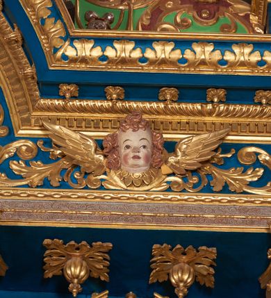 Zdjęcie nr 59: Ołtarz architektoniczny, trójosiowy, dwukondygnacyjny ze zwieńczeniem. Mensa prostopadłościenna, kamienna z drewnianym antepedium w formie leżącego prostokąta z postacią św. Augustyna ujętego wicią suchego akantu z przeplecioną, karbowaną wstążką i bukietami kwiatów. Przedstawienie otoczone profilowaną, ażurową ramą wypełnioną podobną wicią z akantu i kwiatów. Na mensie prostopadłościenne tabernakulum w formie kapliczki. Ściana frontowa z drzwiczkami w kształcie stojącego prostokąta dekorowanego krzyżem łacińskim ujętym wicią roślinną, zwieńczona trójkątnym przyczółkiem. Ścianka ujęta lizenami wypełnionymi wicią akantową podtrzymującymi pełne belkowanie obiegające bryłę, z mocno wysuniętym gzymsem wyłamanym w narożach. Całość zwieńczona czterospadowym dachem dekorowanym łuską. Na dachu baranek Boży leżący na księdze z siedmioma pieczęciami, przytrzymujący chorągiew, ukazany na tle chrystogramu otoczonego glorią promienistą. 
Nastawa na dwudzielnym cokole z półkolistymi bramkami ze zwieńczeniem utworzonym z ornamentu okuciowego ujmującego owalne pola. Osie pierwszej kondygnacji wydzielone kolumnami stojącymi na konsolach dekorowanych z frontu uskrzydlonymi główkami anielskimi powyżej liści akantu, na krawędziach cekinami, a po bokach wicią. Kolumny zostały przedzielone opaską w jednej trzeciej wysokości, dekorowane na całej wysokości wicią roślinną, główkami anielskimi w dolnej partii i imitacją kameryzacji na opaskach oraz w dwóch trzecich wysokości. Kolumny są ustawione na tle pilastrów dekorowanych wicią roślinną i zawieszonymi na niej chustkami. W polu centralnym kondygnacji jest nisza w kształcie stojącego prostokąta zamkniętego łukiem pełnym z postacią ukrzyżowanego Chrystusa na tle widoku Jerozolimy. W osiach bocznych mniejsze, ujęte pilastrami nisze o podobnym kształcie, których konchy wypełnione są muszlą, zwieńczone trójkątnym przyczółkiem przerwanym na cokół. W nich, na dekorowanych wicią i rozetami konsolach ustawiono figury: po lewej stronie św. Piotra, a po prawej św. Pawła. Kondygnacje ujmują ażurowe uszaki utworzone z ornamentu okuciowego, ulistnionych wolut i przewieszonej chustki. Kolumny podtrzymują pełne belkowanie wyniesione w łuk nad polem centralnym. Podłucze dekorowane rozetami, fryz głowami anielskimi i wicią, gzyms m.in. kostkowaniem i liśćmi akantu. Całość spięta kluczem z kartuszem z herbem kanoników regularnych od pokuty (marków). Na wyniesieniu belkowania posadowiono postaci aniołów trzymających narzędzia męki: anioł po lewej włócznię, a anioł po prawej gąbkę. Górna kondygnacja oparta została na schemacie aediculi – prostokątne pole ujęto kolumnami podtrzymującymi pełne belkowanie i trójkątny przyczółek przerwany na środku na cokół, na którym ustawiono rzeźbę  pelikana karmiącego młode własną krwią. Na krawędziach przyczółka dwie leżące postaci. Kondygnacja flankowana postaciami czterech ewangelistów ustawionymi na cokołach. Po lewej stronie św. Marek i św. Jan, po prawej św. Mateusz i św. Łukasz. Struktura polichromowana na kolor ciemnoniebieski; kolumny, profile, detale i ornamenty złocone i srebrzone.
