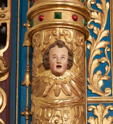 Zdjęcie nr 60: Ołtarz architektoniczny, trójosiowy, dwukondygnacyjny ze zwieńczeniem. Mensa prostopadłościenna, kamienna z drewnianym antepedium w formie leżącego prostokąta z postacią św. Augustyna ujętego wicią suchego akantu z przeplecioną, karbowaną wstążką i bukietami kwiatów. Przedstawienie otoczone profilowaną, ażurową ramą wypełnioną podobną wicią z akantu i kwiatów. Na mensie prostopadłościenne tabernakulum w formie kapliczki. Ściana frontowa z drzwiczkami w kształcie stojącego prostokąta dekorowanego krzyżem łacińskim ujętym wicią roślinną, zwieńczona trójkątnym przyczółkiem. Ścianka ujęta lizenami wypełnionymi wicią akantową podtrzymującymi pełne belkowanie obiegające bryłę, z mocno wysuniętym gzymsem wyłamanym w narożach. Całość zwieńczona czterospadowym dachem dekorowanym łuską. Na dachu baranek Boży leżący na księdze z siedmioma pieczęciami, przytrzymujący chorągiew, ukazany na tle chrystogramu otoczonego glorią promienistą. 
Nastawa na dwudzielnym cokole z półkolistymi bramkami ze zwieńczeniem utworzonym z ornamentu okuciowego ujmującego owalne pola. Osie pierwszej kondygnacji wydzielone kolumnami stojącymi na konsolach dekorowanych z frontu uskrzydlonymi główkami anielskimi powyżej liści akantu, na krawędziach cekinami, a po bokach wicią. Kolumny zostały przedzielone opaską w jednej trzeciej wysokości, dekorowane na całej wysokości wicią roślinną, główkami anielskimi w dolnej partii i imitacją kameryzacji na opaskach oraz w dwóch trzecich wysokości. Kolumny są ustawione na tle pilastrów dekorowanych wicią roślinną i zawieszonymi na niej chustkami. W polu centralnym kondygnacji jest nisza w kształcie stojącego prostokąta zamkniętego łukiem pełnym z postacią ukrzyżowanego Chrystusa na tle widoku Jerozolimy. W osiach bocznych mniejsze, ujęte pilastrami nisze o podobnym kształcie, których konchy wypełnione są muszlą, zwieńczone trójkątnym przyczółkiem przerwanym na cokół. W nich, na dekorowanych wicią i rozetami konsolach ustawiono figury: po lewej stronie św. Piotra, a po prawej św. Pawła. Kondygnacje ujmują ażurowe uszaki utworzone z ornamentu okuciowego, ulistnionych wolut i przewieszonej chustki. Kolumny podtrzymują pełne belkowanie wyniesione w łuk nad polem centralnym. Podłucze dekorowane rozetami, fryz głowami anielskimi i wicią, gzyms m.in. kostkowaniem i liśćmi akantu. Całość spięta kluczem z kartuszem z herbem kanoników regularnych od pokuty (marków). Na wyniesieniu belkowania posadowiono postaci aniołów trzymających narzędzia męki: anioł po lewej włócznię, a anioł po prawej gąbkę. Górna kondygnacja oparta została na schemacie aediculi – prostokątne pole ujęto kolumnami podtrzymującymi pełne belkowanie i trójkątny przyczółek przerwany na środku na cokół, na którym ustawiono rzeźbę  pelikana karmiącego młode własną krwią. Na krawędziach przyczółka dwie leżące postaci. Kondygnacja flankowana postaciami czterech ewangelistów ustawionymi na cokołach. Po lewej stronie św. Marek i św. Jan, po prawej św. Mateusz i św. Łukasz. Struktura polichromowana na kolor ciemnoniebieski; kolumny, profile, detale i ornamenty złocone i srebrzone.
