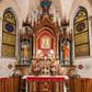 Zdjęcie nr 1: Ołtarz jednokondygnacyjny na wysokim, schodkowym cokole, trójosiowy, z wysuniętą mensą ołtarzową. Płyciny cokołu zdobione dekoracją w formie ostrołukowych maswerków i rozet w kwadratowej ramie. Antepedium flankowane parą kolumn ustawionych na wysokich cokołach i kanelowanych, skręconych trzonach z kompozytowymi kapitelami. W polu dwie prostokątne płyciny i kwadratowa pośrodku ze stylizowaną wicią roślinną i małą uskrzydloną główką aniołka. Tabernakulum proste, w kształcie prostopadłościennej skrzynki, o złotych drzwiczkach z wytłaczaną formą równoramiennego krzyża i wypukłą srebrną rybą oraz koszem z chlebem. Po obu stronach, na niewysokich postumentach dwa klęczące anioły z wysokimi skrzydłami, w biało różowych szatach z fioletowym podbiciem (skrzydła stylizowane na husarskie). Anioł po lewej z kadzielnicą, a anioł po prawej z kielichem.
Nastawa ołtarzowa o trzech oddzielnych niszach, nakrytych gotycyzującymi baldachimami z pinaklami, ozdobionymi żabkami. Oś środkowa w formie niszy zamkniętej ostrołukowo z wimpergą wspartą na smukłych, złoconych kolumienkach o kapitelach kompozytowych. Wimperga ze złoconymi, profilowanymi płycinami, zwieńczona rzeźbionymi liśćmi akantu i wolutami. Na przedłużeniu kolumn postumenty z figurami aniołów w biało niebieskich szatach, ze złotymi, wydłużonymi skrzydłami. Na osi na postumencie, pod gotycyzującym baldachimem figura świętego biskupa w czerwonej szacie z krzyżem w dłoni pomiędzy dwoma aniołami w białych i różowych szatach. W niszy, na czerwonym tle obraz Matki Boskiej Nieustającej Pomocy w prostej ramie z dekoracją w formie wici roślinnej. Poniżej dwa płaskorzeźbione anioły trzymające ażurowy monogram maryjny. Anioły o pozłacanych skrzydłach, na chmurach, w różowej i niebieskiej szacie. Osie boczne w formie aediculi z gotycyzującym baldachimem. W niszach figury, po lewej św. Piotra, a po prawej św. Pawła. Aedicule ujęte są smukłymi, skręconymi kolumnami z kapitelami wolutowymi oraz roślinnym uszakiem z perełkowaniem. Nad nimi imposty, na których rzeźby osłaniane baldachimami, po lewej świętego w habicie jezuity, a po prawej św. Jana Kantego. Drewno bejcowane na ciemny brąz, z nakładanymi elementami dekoracyjnymi złoconymi. 