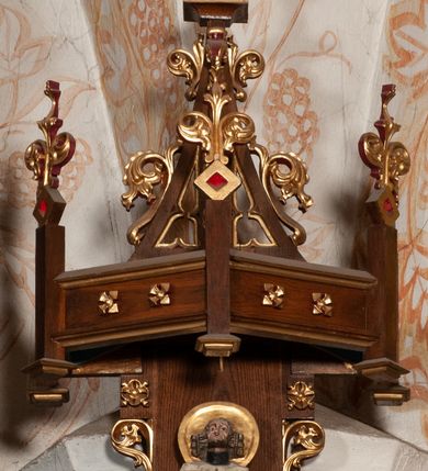 Zdjęcie nr 6: Ołtarz jednokondygnacyjny na wysokim, schodkowym cokole, trójosiowy, z wysuniętą mensą ołtarzową. Płyciny cokołu zdobione dekoracją w formie ostrołukowych maswerków i rozet w kwadratowej ramie. Antepedium flankowane parą kolumn ustawionych na wysokich cokołach i kanelowanych, skręconych trzonach z kompozytowymi kapitelami. W polu dwie prostokątne płyciny i kwadratowa pośrodku ze stylizowaną wicią roślinną i małą uskrzydloną główką aniołka. Tabernakulum proste, w kształcie prostopadłościennej skrzynki, o złotych drzwiczkach z wytłaczaną formą równoramiennego krzyża i wypukłą srebrną rybą oraz koszem z chlebem. Po obu stronach, na niewysokich postumentach dwa klęczące anioły z wysokimi skrzydłami, w biało różowych szatach z fioletowym podbiciem (skrzydła stylizowane na husarskie). Anioł po lewej z kadzielnicą, a anioł po prawej z kielichem.
Nastawa ołtarzowa o trzech oddzielnych niszach, nakrytych gotycyzującymi baldachimami z pinaklami, ozdobionymi żabkami. Oś środkowa w formie niszy zamkniętej ostrołukowo z wimpergą wspartą na smukłych, złoconych kolumienkach o kapitelach kompozytowych. Wimperga ze złoconymi, profilowanymi płycinami, zwieńczona rzeźbionymi liśćmi akantu i wolutami. Na przedłużeniu kolumn postumenty z figurami aniołów w biało niebieskich szatach, ze złotymi, wydłużonymi skrzydłami. Na osi na postumencie, pod gotycyzującym baldachimem figura świętego biskupa w czerwonej szacie z krzyżem w dłoni pomiędzy dwoma aniołami w białych i różowych szatach. W niszy, na czerwonym tle obraz Matki Boskiej Nieustającej Pomocy w prostej ramie z dekoracją w formie wici roślinnej. Poniżej dwa płaskorzeźbione anioły trzymające ażurowy monogram maryjny. Anioły o pozłacanych skrzydłach, na chmurach, w różowej i niebieskiej szacie. Osie boczne w formie aediculi z gotycyzującym baldachimem. W niszach figury, po lewej św. Piotra, a po prawej św. Pawła. Aedicule ujęte są smukłymi, skręconymi kolumnami z kapitelami wolutowymi oraz roślinnym uszakiem z perełkowaniem. Nad nimi imposty, na których rzeźby osłaniane baldachimami, po lewej świętego w habicie jezuity, a po prawej św. Jana Kantego. Drewno bejcowane na ciemny brąz, z nakładanymi elementami dekoracyjnymi złoconymi. 