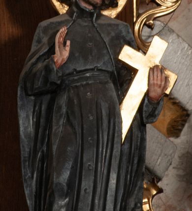 Zdjęcie nr 3: Ołtarz jednokondygnacyjny na wysokim, schodkowym cokole, trójosiowy, z wysuniętą mensą ołtarzową. Płyciny cokołu zdobione dekoracją w formie ostrołukowych maswerków i rozet w kwadratowej ramie. Antepedium flankowane parą kolumn ustawionych na wysokich cokołach i kanelowanych, skręconych trzonach z kompozytowymi kapitelami. W polu dwie prostokątne płyciny i kwadratowa pośrodku ze stylizowaną wicią roślinną i małą uskrzydloną główką aniołka. Tabernakulum proste, w kształcie prostopadłościennej skrzynki, o złotych drzwiczkach z wytłaczaną formą równoramiennego krzyża i wypukłą srebrną rybą oraz koszem z chlebem. Po obu stronach, na niewysokich postumentach dwa klęczące anioły z wysokimi skrzydłami, w biało różowych szatach z fioletowym podbiciem (skrzydła stylizowane na husarskie). Anioł po lewej z kadzielnicą, a anioł po prawej z kielichem.
Nastawa ołtarzowa o trzech oddzielnych niszach, nakrytych gotycyzującymi baldachimami z pinaklami, ozdobionymi żabkami. Oś środkowa w formie niszy zamkniętej ostrołukowo z wimpergą wspartą na smukłych, złoconych kolumienkach o kapitelach kompozytowych. Wimperga ze złoconymi, profilowanymi płycinami, zwieńczona rzeźbionymi liśćmi akantu i wolutami. Na przedłużeniu kolumn postumenty z figurami aniołów w biało niebieskich szatach, ze złotymi, wydłużonymi skrzydłami. Na osi na postumencie, pod gotycyzującym baldachimem figura świętego biskupa w czerwonej szacie z krzyżem w dłoni pomiędzy dwoma aniołami w białych i różowych szatach. W niszy, na czerwonym tle obraz Matki Boskiej Nieustającej Pomocy w prostej ramie z dekoracją w formie wici roślinnej. Poniżej dwa płaskorzeźbione anioły trzymające ażurowy monogram maryjny. Anioły o pozłacanych skrzydłach, na chmurach, w różowej i niebieskiej szacie. Osie boczne w formie aediculi z gotycyzującym baldachimem. W niszach figury, po lewej św. Piotra, a po prawej św. Pawła. Aedicule ujęte są smukłymi, skręconymi kolumnami z kapitelami wolutowymi oraz roślinnym uszakiem z perełkowaniem. Nad nimi imposty, na których rzeźby osłaniane baldachimami, po lewej świętego w habicie jezuity, a po prawej św. Jana Kantego. Drewno bejcowane na ciemny brąz, z nakładanymi elementami dekoracyjnymi złoconymi. 