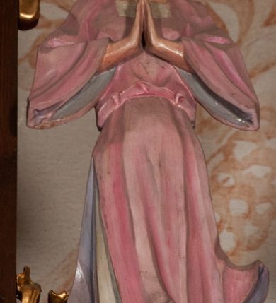 Zdjęcie nr 12: Ołtarz jednokondygnacyjny na wysokim, schodkowym cokole, trójosiowy, z wysuniętą mensą ołtarzową. Płyciny cokołu zdobione dekoracją w formie ostrołukowych maswerków i rozet w kwadratowej ramie. Antepedium flankowane parą kolumn ustawionych na wysokich cokołach i kanelowanych, skręconych trzonach z kompozytowymi kapitelami. W polu dwie prostokątne płyciny i kwadratowa pośrodku ze stylizowaną wicią roślinną i małą uskrzydloną główką aniołka. Tabernakulum proste, w kształcie prostopadłościennej skrzynki, o złotych drzwiczkach z wytłaczaną formą równoramiennego krzyża i wypukłą srebrną rybą oraz koszem z chlebem. Po obu stronach, na niewysokich postumentach dwa klęczące anioły z wysokimi skrzydłami, w biało różowych szatach z fioletowym podbiciem (skrzydła stylizowane na husarskie). Anioł po lewej z kadzielnicą, a anioł po prawej z kielichem.
Nastawa ołtarzowa o trzech oddzielnych niszach, nakrytych gotycyzującymi baldachimami z pinaklami, ozdobionymi żabkami. Oś środkowa w formie niszy zamkniętej ostrołukowo z wimpergą wspartą na smukłych, złoconych kolumienkach o kapitelach kompozytowych. Wimperga ze złoconymi, profilowanymi płycinami, zwieńczona rzeźbionymi liśćmi akantu i wolutami. Na przedłużeniu kolumn postumenty z figurami aniołów w biało niebieskich szatach, ze złotymi, wydłużonymi skrzydłami. Na osi na postumencie, pod gotycyzującym baldachimem figura świętego biskupa w czerwonej szacie z krzyżem w dłoni pomiędzy dwoma aniołami w białych i różowych szatach. W niszy, na czerwonym tle obraz Matki Boskiej Nieustającej Pomocy w prostej ramie z dekoracją w formie wici roślinnej. Poniżej dwa płaskorzeźbione anioły trzymające ażurowy monogram maryjny. Anioły o pozłacanych skrzydłach, na chmurach, w różowej i niebieskiej szacie. Osie boczne w formie aediculi z gotycyzującym baldachimem. W niszach figury, po lewej św. Piotra, a po prawej św. Pawła. Aedicule ujęte są smukłymi, skręconymi kolumnami z kapitelami wolutowymi oraz roślinnym uszakiem z perełkowaniem. Nad nimi imposty, na których rzeźby osłaniane baldachimami, po lewej świętego w habicie jezuity, a po prawej św. Jana Kantego. Drewno bejcowane na ciemny brąz, z nakładanymi elementami dekoracyjnymi złoconymi. 