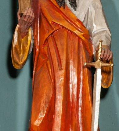 Zdjęcie nr 21: Ołtarz jednokondygnacyjny na wysokim, schodkowym cokole, trójosiowy, z wysuniętą mensą ołtarzową. Płyciny cokołu zdobione dekoracją w formie ostrołukowych maswerków i rozet w kwadratowej ramie. Antepedium flankowane parą kolumn ustawionych na wysokich cokołach i kanelowanych, skręconych trzonach z kompozytowymi kapitelami. W polu dwie prostokątne płyciny i kwadratowa pośrodku ze stylizowaną wicią roślinną i małą uskrzydloną główką aniołka. Tabernakulum proste, w kształcie prostopadłościennej skrzynki, o złotych drzwiczkach z wytłaczaną formą równoramiennego krzyża i wypukłą srebrną rybą oraz koszem z chlebem. Po obu stronach, na niewysokich postumentach dwa klęczące anioły z wysokimi skrzydłami, w biało różowych szatach z fioletowym podbiciem (skrzydła stylizowane na husarskie). Anioł po lewej z kadzielnicą, a anioł po prawej z kielichem.
Nastawa ołtarzowa o trzech oddzielnych niszach, nakrytych gotycyzującymi baldachimami z pinaklami, ozdobionymi żabkami. Oś środkowa w formie niszy zamkniętej ostrołukowo z wimpergą wspartą na smukłych, złoconych kolumienkach o kapitelach kompozytowych. Wimperga ze złoconymi, profilowanymi płycinami, zwieńczona rzeźbionymi liśćmi akantu i wolutami. Na przedłużeniu kolumn postumenty z figurami aniołów w biało niebieskich szatach, ze złotymi, wydłużonymi skrzydłami. Na osi na postumencie, pod gotycyzującym baldachimem figura świętego biskupa w czerwonej szacie z krzyżem w dłoni pomiędzy dwoma aniołami w białych i różowych szatach. W niszy, na czerwonym tle obraz Matki Boskiej Nieustającej Pomocy w prostej ramie z dekoracją w formie wici roślinnej. Poniżej dwa płaskorzeźbione anioły trzymające ażurowy monogram maryjny. Anioły o pozłacanych skrzydłach, na chmurach, w różowej i niebieskiej szacie. Osie boczne w formie aediculi z gotycyzującym baldachimem. W niszach figury, po lewej św. Piotra, a po prawej św. Pawła. Aedicule ujęte są smukłymi, skręconymi kolumnami z kapitelami wolutowymi oraz roślinnym uszakiem z perełkowaniem. Nad nimi imposty, na których rzeźby osłaniane baldachimami, po lewej świętego w habicie jezuity, a po prawej św. Jana Kantego. Drewno bejcowane na ciemny brąz, z nakładanymi elementami dekoracyjnymi złoconymi. 