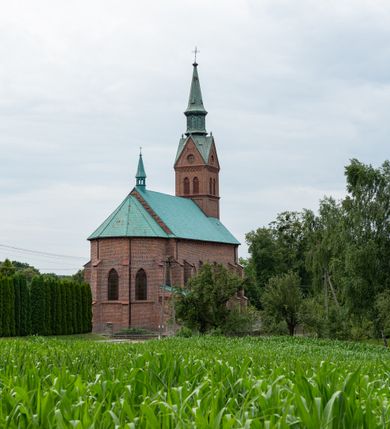 Zdjęcie nr 6: Kościół ceglany, na planie prostokąta z węższym i niższym prezbiterium z zakrystią od północy i wieżą od zachodu. Kościół orientowany, jednonawowy, czteroprzęsłowy z węższym, jednoprzęsłowym prezbiterium zamkniętym trójbocznie, z kruchtą w przyziemiu wieży. Nawa artykułowana półfilarami o ściętych narożach, przechodzącymi w zamknięte łukiem ostrym gurty krzyżowo-żebrowego sklepienia. W nawie i prezbiterium okna prostokątne zamknięte łukiem ostrym – pięć w prezbiterium, po trzy z każdej strony nawy. Węższe okna w przęśle chóru, kolejne w fasadzie. Główne wejście od wschodu, drugie od zachodu. Chór muzyczny w czwartym przęśle nawy, wsparty na wielobocznych filarach, podtrzymujących ostrołukowe arkady, z parapetem ozdobionym blendami. Ściany w dolnej partii pokryte drewnianą boazerią, wyżej malowane na kremowo, w partiach sklepienia polichromia podkreślająca elementy konstrukcji fragmentami stylizowanej wici i dekoracji floralnej; na belce tęczowej anioły niosące plakiety z symbolami świętych sakramentów. Fasada trójosiowa, z ryzalitem szerokości wieży oszkarpowanym na narożach. Podziały poziome przeprowadzone przy pomocy gzymsów. Na osi ostrołukowe wejście, powyżej wypełniony maswerkiem okulus. Następna kondygnacja jest częścią czworobocznej wieży, wypełniono ją dużym oknem w kształcę stojącego prostokąta zamkniętego łukiem ostrym.  Boczne osie z małymi oknami powtarzającymi kształt pozostałych, zamknięte trójkątnym przyczółkiem przerwanym na wieżę. Najwyższa kondygnacja wieży przepruta z każdej strony parą okien w kształcie stojących prostokątów umieszczonych w ostrołukowych niszach. Wieńczący ją gzyms dekorowany zygzakiem, powyżej trójkątne szczyty z ostrołukową blendą z okulusem w centrum. Elewacje boczne i prezbiterium oszkarpowane, przeprute oknami.  Hełm wieży w formie latarni zakończonej stożkiem z kupą i krzyżem, nawa przekryta dachem dwuspadowym, prezbiterium wielobocznym, zakrystia i wejście od zachodu pulpitowymi. 


Do najciekawszych elementów wyposażenia należą zespół neogotyckich ołtarzy wraz z amboną oraz kolekcja dziewiętnastowiecznych feretronów. W otoczeniu kościoła znajduje się kamienna figura św. Jana Nepomucena z 1788 roku. 
