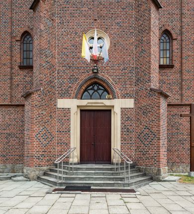 Zdjęcie nr 11: Kościół ceglany, na planie prostokąta z węższym i niższym prezbiterium z zakrystią od północy i wieżą od zachodu. Kościół orientowany, jednonawowy, czteroprzęsłowy z węższym, jednoprzęsłowym prezbiterium zamkniętym trójbocznie, z kruchtą w przyziemiu wieży. Nawa artykułowana półfilarami o ściętych narożach, przechodzącymi w zamknięte łukiem ostrym gurty krzyżowo-żebrowego sklepienia. W nawie i prezbiterium okna prostokątne zamknięte łukiem ostrym – pięć w prezbiterium, po trzy z każdej strony nawy. Węższe okna w przęśle chóru, kolejne w fasadzie. Główne wejście od wschodu, drugie od zachodu. Chór muzyczny w czwartym przęśle nawy, wsparty na wielobocznych filarach, podtrzymujących ostrołukowe arkady, z parapetem ozdobionym blendami. Ściany w dolnej partii pokryte drewnianą boazerią, wyżej malowane na kremowo, w partiach sklepienia polichromia podkreślająca elementy konstrukcji fragmentami stylizowanej wici i dekoracji floralnej; na belce tęczowej anioły niosące plakiety z symbolami świętych sakramentów. Fasada trójosiowa, z ryzalitem szerokości wieży oszkarpowanym na narożach. Podziały poziome przeprowadzone przy pomocy gzymsów. Na osi ostrołukowe wejście, powyżej wypełniony maswerkiem okulus. Następna kondygnacja jest częścią czworobocznej wieży, wypełniono ją dużym oknem w kształcę stojącego prostokąta zamkniętego łukiem ostrym.  Boczne osie z małymi oknami powtarzającymi kształt pozostałych, zamknięte trójkątnym przyczółkiem przerwanym na wieżę. Najwyższa kondygnacja wieży przepruta z każdej strony parą okien w kształcie stojących prostokątów umieszczonych w ostrołukowych niszach. Wieńczący ją gzyms dekorowany zygzakiem, powyżej trójkątne szczyty z ostrołukową blendą z okulusem w centrum. Elewacje boczne i prezbiterium oszkarpowane, przeprute oknami.  Hełm wieży w formie latarni zakończonej stożkiem z kupą i krzyżem, nawa przekryta dachem dwuspadowym, prezbiterium wielobocznym, zakrystia i wejście od zachodu pulpitowymi. 


Do najciekawszych elementów wyposażenia należą zespół neogotyckich ołtarzy wraz z amboną oraz kolekcja dziewiętnastowiecznych feretronów. W otoczeniu kościoła znajduje się kamienna figura św. Jana Nepomucena z 1788 roku. 
