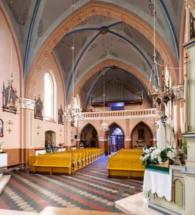 Zdjęcie nr 21: Kościół ceglany, na planie prostokąta z węższym i niższym prezbiterium z zakrystią od północy i wieżą od zachodu. Kościół orientowany, jednonawowy, czteroprzęsłowy z węższym, jednoprzęsłowym prezbiterium zamkniętym trójbocznie, z kruchtą w przyziemiu wieży. Nawa artykułowana półfilarami o ściętych narożach, przechodzącymi w zamknięte łukiem ostrym gurty krzyżowo-żebrowego sklepienia. W nawie i prezbiterium okna prostokątne zamknięte łukiem ostrym – pięć w prezbiterium, po trzy z każdej strony nawy. Węższe okna w przęśle chóru, kolejne w fasadzie. Główne wejście od wschodu, drugie od zachodu. Chór muzyczny w czwartym przęśle nawy, wsparty na wielobocznych filarach, podtrzymujących ostrołukowe arkady, z parapetem ozdobionym blendami. Ściany w dolnej partii pokryte drewnianą boazerią, wyżej malowane na kremowo, w partiach sklepienia polichromia podkreślająca elementy konstrukcji fragmentami stylizowanej wici i dekoracji floralnej; na belce tęczowej anioły niosące plakiety z symbolami świętych sakramentów. Fasada trójosiowa, z ryzalitem szerokości wieży oszkarpowanym na narożach. Podziały poziome przeprowadzone przy pomocy gzymsów. Na osi ostrołukowe wejście, powyżej wypełniony maswerkiem okulus. Następna kondygnacja jest częścią czworobocznej wieży, wypełniono ją dużym oknem w kształcę stojącego prostokąta zamkniętego łukiem ostrym.  Boczne osie z małymi oknami powtarzającymi kształt pozostałych, zamknięte trójkątnym przyczółkiem przerwanym na wieżę. Najwyższa kondygnacja wieży przepruta z każdej strony parą okien w kształcie stojących prostokątów umieszczonych w ostrołukowych niszach. Wieńczący ją gzyms dekorowany zygzakiem, powyżej trójkątne szczyty z ostrołukową blendą z okulusem w centrum. Elewacje boczne i prezbiterium oszkarpowane, przeprute oknami.  Hełm wieży w formie latarni zakończonej stożkiem z kupą i krzyżem, nawa przekryta dachem dwuspadowym, prezbiterium wielobocznym, zakrystia i wejście od zachodu pulpitowymi. 


Do najciekawszych elementów wyposażenia należą zespół neogotyckich ołtarzy wraz z amboną oraz kolekcja dziewiętnastowiecznych feretronów. W otoczeniu kościoła znajduje się kamienna figura św. Jana Nepomucena z 1788 roku. 
