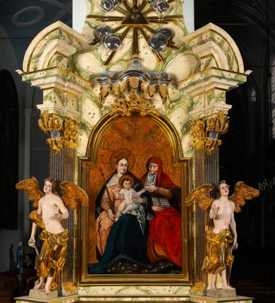 Zdjęcie nr 24: Ołtarz architektoniczny, jednoosiowy, jednokondygnacyjny, ze zwieńczeniem. Ołtarz prostopadłościenny z drewnianą, współczesną mensą i współczesnym antependium z przedstawieniem świętej w otoczeniu wieńca z kwiatami. Nastawa ujęta ukośnie dostawionymi filarami kanelowanymi, ustawionymi na postumentach z konsolami o prostych kapitelach utworzonych z roccailli i konsol podtrzymujących przerwane belkowanie zwieńczone ćwierćkolistymi naczółkami. Zwieńczenie o wklęsłych bokach zakończone profilowanym gzymsem w kształcie łuku nadwieszonego półkolistego. Na tle filaru, na konsolach ustawione figury uskrzydlonych aniołów. W polu środkowym obraz w kształcie stojącego prostokąta zamkniętego łukiem nadwieszonym półkolistym ozdobiony rocaillem. W ramie obraz z przedstawieniem św. Anny Samotrzeciej z Madonną z Dzieciątkiem. Nad ramą baldachim z lambrekinem. W zwieńczeniu serce Gorejące na tle glorii promienistej z chmurkami, zwieńczonej uskrzydloną główką anielską; nad gzymsem zwieńczenia  grzebień utworzony z ażurowego rocaillu. 