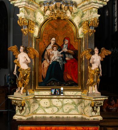 Zdjęcie nr 13: Ołtarz architektoniczny, jednoosiowy, jednokondygnacyjny, ze zwieńczeniem. Ołtarz prostopadłościenny z drewnianą, współczesną mensą i współczesnym antependium z przedstawieniem świętej w otoczeniu wieńca z kwiatami. Nastawa ujęta ukośnie dostawionymi filarami kanelowanymi, ustawionymi na postumentach z konsolami o prostych kapitelach utworzonych z roccailli i konsol podtrzymujących przerwane belkowanie zwieńczone ćwierćkolistymi naczółkami. Zwieńczenie o wklęsłych bokach zakończone profilowanym gzymsem w kształcie łuku nadwieszonego półkolistego. Na tle filaru, na konsolach ustawione figury uskrzydlonych aniołów. W polu środkowym obraz w kształcie stojącego prostokąta zamkniętego łukiem nadwieszonym półkolistym ozdobiony rocaillem. W ramie obraz z przedstawieniem św. Anny Samotrzeciej z Madonną z Dzieciątkiem. Nad ramą baldachim z lambrekinem. W zwieńczeniu serce Gorejące na tle glorii promienistej z chmurkami, zwieńczonej uskrzydloną główką anielską; nad gzymsem zwieńczenia  grzebień utworzony z ażurowego rocaillu. 