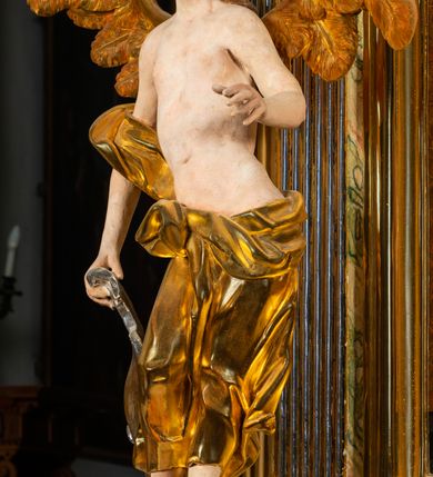 Zdjęcie nr 14: Ołtarz architektoniczny, jednoosiowy, jednokondygnacyjny, ze zwieńczeniem. Ołtarz prostopadłościenny z drewnianą, współczesną mensą i współczesnym antependium z przedstawieniem świętej w otoczeniu wieńca z kwiatami. Nastawa ujęta ukośnie dostawionymi filarami kanelowanymi, ustawionymi na postumentach z konsolami o prostych kapitelach utworzonych z roccailli i konsol podtrzymujących przerwane belkowanie zwieńczone ćwierćkolistymi naczółkami. Zwieńczenie o wklęsłych bokach zakończone profilowanym gzymsem w kształcie łuku nadwieszonego półkolistego. Na tle filaru, na konsolach ustawione figury uskrzydlonych aniołów. W polu środkowym obraz w kształcie stojącego prostokąta zamkniętego łukiem nadwieszonym półkolistym ozdobiony rocaillem. W ramie obraz z przedstawieniem św. Anny Samotrzeciej z Madonną z Dzieciątkiem. Nad ramą baldachim z lambrekinem. W zwieńczeniu serce Gorejące na tle glorii promienistej z chmurkami, zwieńczonej uskrzydloną główką anielską; nad gzymsem zwieńczenia  grzebień utworzony z ażurowego rocaillu. 