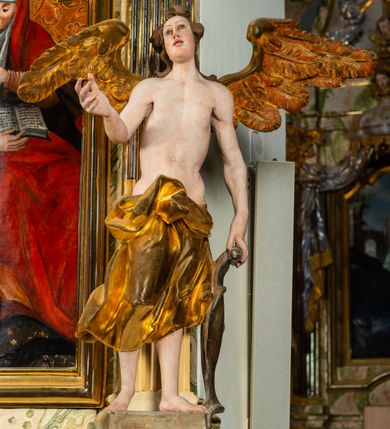 Zdjęcie nr 19: Ołtarz architektoniczny, jednoosiowy, jednokondygnacyjny, ze zwieńczeniem. Ołtarz prostopadłościenny z drewnianą, współczesną mensą i współczesnym antependium z przedstawieniem świętej w otoczeniu wieńca z kwiatami. Nastawa ujęta ukośnie dostawionymi filarami kanelowanymi, ustawionymi na postumentach z konsolami o prostych kapitelach utworzonych z roccailli i konsol podtrzymujących przerwane belkowanie zwieńczone ćwierćkolistymi naczółkami. Zwieńczenie o wklęsłych bokach zakończone profilowanym gzymsem w kształcie łuku nadwieszonego półkolistego. Na tle filaru, na konsolach ustawione figury uskrzydlonych aniołów. W polu środkowym obraz w kształcie stojącego prostokąta zamkniętego łukiem nadwieszonym półkolistym ozdobiony rocaillem. W ramie obraz z przedstawieniem św. Anny Samotrzeciej z Madonną z Dzieciątkiem. Nad ramą baldachim z lambrekinem. W zwieńczeniu serce Gorejące na tle glorii promienistej z chmurkami, zwieńczonej uskrzydloną główką anielską; nad gzymsem zwieńczenia  grzebień utworzony z ażurowego rocaillu. 