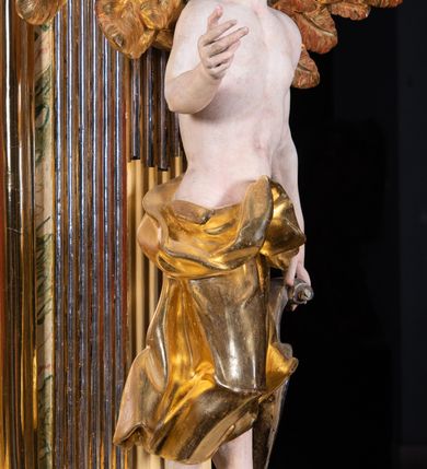 Zdjęcie nr 21: Ołtarz architektoniczny, jednoosiowy, jednokondygnacyjny, ze zwieńczeniem. Ołtarz prostopadłościenny z drewnianą, współczesną mensą i współczesnym antependium z przedstawieniem świętej w otoczeniu wieńca z kwiatami. Nastawa ujęta ukośnie dostawionymi filarami kanelowanymi, ustawionymi na postumentach z konsolami o prostych kapitelach utworzonych z roccailli i konsol podtrzymujących przerwane belkowanie zwieńczone ćwierćkolistymi naczółkami. Zwieńczenie o wklęsłych bokach zakończone profilowanym gzymsem w kształcie łuku nadwieszonego półkolistego. Na tle filaru, na konsolach ustawione figury uskrzydlonych aniołów. W polu środkowym obraz w kształcie stojącego prostokąta zamkniętego łukiem nadwieszonym półkolistym ozdobiony rocaillem. W ramie obraz z przedstawieniem św. Anny Samotrzeciej z Madonną z Dzieciątkiem. Nad ramą baldachim z lambrekinem. W zwieńczeniu serce Gorejące na tle glorii promienistej z chmurkami, zwieńczonej uskrzydloną główką anielską; nad gzymsem zwieńczenia  grzebień utworzony z ażurowego rocaillu. 