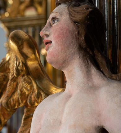 Zdjęcie nr 29: Ołtarz architektoniczny, jednoosiowy, jednokondygnacyjny, ze zwieńczeniem. Ołtarz prostopadłościenny z drewnianą, współczesną mensą i współczesnym antependium z przedstawieniem świętej w otoczeniu wieńca z kwiatami. Nastawa ujęta ukośnie dostawionymi filarami kanelowanymi, ustawionymi na postumentach z konsolami o prostych kapitelach utworzonych z roccailli i konsol podtrzymujących przerwane belkowanie zwieńczone ćwierćkolistymi naczółkami. Zwieńczenie o wklęsłych bokach zakończone profilowanym gzymsem w kształcie łuku nadwieszonego półkolistego. Na tle filaru, na konsolach ustawione figury uskrzydlonych aniołów. W polu środkowym obraz w kształcie stojącego prostokąta zamkniętego łukiem nadwieszonym półkolistym ozdobiony rocaillem. W ramie obraz z przedstawieniem św. Anny Samotrzeciej z Madonną z Dzieciątkiem. Nad ramą baldachim z lambrekinem. W zwieńczeniu serce Gorejące na tle glorii promienistej z chmurkami, zwieńczonej uskrzydloną główką anielską; nad gzymsem zwieńczenia  grzebień utworzony z ażurowego rocaillu. 