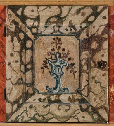 Zdjęcie nr 111: Umeblowanie zakrystii usytuowane jest wzdłuż ścian północnej, południowej i wschodniej pomieszczenia.  Na ścianie północnej, w części dolnej znajdują się trzy połączone ze sobą komody, każda o czterech szufladach, nakryte jednym blatem. W części górnej mieszczą się pięcioosiowe szafki z szufladami w cokole. Osie artykułowe są pilastrami hermowymi. Na osi środkowej szafka jest nieco wyższa i szersza z drzwiczkami dekorowanymi prostokątną, uszatą, oprofilowaną płyciną z malowanym przedstawieniem Chrystusa Eucharystycznego. Drzwiczki pozostałych szafek mają kształt stojących prostokątów i dekorowane są płycinami o wklęsłych narożach, zdobionymi gałązkami czerwonych róż, ułożonych w rokokowych wazonach. Ścianki zamknięte są niepełnym belkowaniem z gzymsem. W partii zwieńczenia osie artykułowane są cokolikami, na których ustawione są toczone, kuliste wazoniki. Pomiędzy nimi umieszczone są kartusze utworzone z ornamentu małżowinowo-chrząstkowego z malowanymi emblematami na owalnych medalionach, które ułożone są kolejno od lewej strony: 
1. Pionowo ustawiony miecz, ostrzem skierowany ku górze, połączony ze skrzyżowanymi berłem i dwoma kluczami, od których odchodzą fantazyjnie ułożone sznury w kolorze czerwonym. U góry napis na szarfie: „OBEDITE”.
2. W górnej części wyłaniająca się z chmur ręka trzymająca w dłoni węgielnicę i przymocowane do niej na łańcuszku tablice Dekalogu. Napis na szarfie: „OMNIA SVSTINET”.
3. Bóg Ojciec ukazany w półpostaci, lewą ręką opiera się na kuli ziemskiej, prawą czyni gest błogosławieństwa. 
4. Bujnie ulistnione, ciemnozielone drzewko spięte w dolnej części złotą formą w kształcie dwóch wywiniętych wolutek. Napis na szarfie: „GAVDET PATIENTIA DVRIS”. 
5. W górnej części obrazu z chmur wyłania się ręka, która zrzuca na ziemię iskrzący pocisk i dwa skrzyżowane pioruny, połączone parą białych skrzydeł. Napis „FORTIS VLTOR”.
 
Na ścianie środkowej, wschodniej znajduje się sarkofagowa mensa, powyżej parawanowa ścianka na profilowanym cokole, artykułowana pilastrami, pomiędzy którymi umieszczone są płyciny z kształcie leżących prostokątów z obrazami; ścianka zamknięta jest profilowanym gzymsem. W zwieńczeniu, na jej skrajach znajdują się owalne medaliony ujęte w kartusze z ornamentu małżowinowo-chrząstkowego. W medalionie po lewej stronie namalowane są litery alfa i omega na błękitnym tle oraz wstęga z napisem: „RENOVATUM A(NNO) D(OMINI) 1975”. Po prawej stronie analogiczny kartusz z literami w medalionie: „Ω / O / N” wpisane w formę krzyża, otoczonego niepełną aureolą; powyżej wstęga z napisem: „VIDENTEM AUDERE”. W płycinach obrazy przedstawiają świętych w ujęciu do pasa, zwróconych ku środkowi; od lewej:
1. Święty Demetriusz z włócznią opartą o prawy bark, ubrany w habit zakonu kanoników laterańskich od pokuty.
2. Święty Klet z aniołkiem, który trzyma w dłoni palmę męczeństwa i krzyż papieski. W prawym górnym narożu obrazu napis: „FAC HVIC SIGNO HONOREM”.
3. Święty Augustyn z gorejącym sercem na piersi i aniołkiem z łyżką i miseczką w dłoniach.
4. Święty ubrany w habit Marków, który trzyma w dłoni serce z krzyżem, podtrzymywane przez Chrystusa na obłokach – prawdopodobnie św. Cyriak, założyciel zakonu.
 
Na ścianie południowej znajduje się analogiczne umeblowanie, jak na ścianie północnej. W dolnej części dwie komody, a w miejscu trzeciej od wschodu szafka zdobiona dwiema uszatymi płycinami. Górna część mebla w przeciwieństwie do ściany północnej bez podwyższenia części środkowej. 
Na ścianie południowej:
1. Jasnobrązowa harfa na błękitnym tle i napis: „IN DOMINO”.
2. Ciemnobrązowy ptak i trzy podrywające się do lotu młode, w górnej części złote słońce i napis: „NON QUAE SVPER TERRAM.”
3. Po lewej stronie kompozycji wyłaniająca się z chmur ręka trzymająca skrzyżowane: miecz, czerwony krzyż i palmę. Napis: „NON ERVBESCO”.
4. W centrum przedstawienia krzak białej lilii o trzech rozgałęzieniach, w tle chmury w odcieniach koloru szaroniebieskiego. Napis na szarfie: „PER ARDVA DVLCIS”.
5. W lewej części kompozycji uskrzydlony jeleń, wspięty na tylnych nogach, po prawej stronie czarne i brązowe skały, w partii górnej otwarta korona, umieszczona pośrodku obłoku obwiedzionego biało-czerwonym pasem. Napis: „ET COMPREHENDATIS”.
 
W miejscu połączenia komód ścian północnej i południowej z dolną częścią konstrukcji na ścianie wschodniej znajdują się ukośnie ustawione, jednoskrzydłowe szafki o drzwiczkach dekorowanych prostokątną płyciną o wklęsłych narożach. Ścianki boczne części północnej i południowej zdobione są ukośną kratką. Powierzchnia szafek i komód pokryta jest polichromią imitującą marmur w kolorze beżowym, szarokremowym, różowym i rdzawym. Blaty malowane są farbą olejną w kolorze beżowym. Obramienia medalionów malowane w kolorze rdzawozłotym. Tło w większości medalionów w odcieniach błękitu, w górnych częściach majuskułowe napisy objaśniające przedstawienie, umieszczone w białych i półkoliście ułożonych szarfach. 