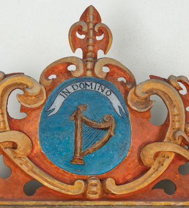 Zdjęcie nr 41: Umeblowanie zakrystii usytuowane jest wzdłuż ścian północnej, południowej i wschodniej pomieszczenia.  Na ścianie północnej, w części dolnej znajdują się trzy połączone ze sobą komody, każda o czterech szufladach, nakryte jednym blatem. W części górnej mieszczą się pięcioosiowe szafki z szufladami w cokole. Osie artykułowe są pilastrami hermowymi. Na osi środkowej szafka jest nieco wyższa i szersza z drzwiczkami dekorowanymi prostokątną, uszatą, oprofilowaną płyciną z malowanym przedstawieniem Chrystusa Eucharystycznego. Drzwiczki pozostałych szafek mają kształt stojących prostokątów i dekorowane są płycinami o wklęsłych narożach, zdobionymi gałązkami czerwonych róż, ułożonych w rokokowych wazonach. Ścianki zamknięte są niepełnym belkowaniem z gzymsem. W partii zwieńczenia osie artykułowane są cokolikami, na których ustawione są toczone, kuliste wazoniki. Pomiędzy nimi umieszczone są kartusze utworzone z ornamentu małżowinowo-chrząstkowego z malowanymi emblematami na owalnych medalionach, które ułożone są kolejno od lewej strony: 
1. Pionowo ustawiony miecz, ostrzem skierowany ku górze, połączony ze skrzyżowanymi berłem i dwoma kluczami, od których odchodzą fantazyjnie ułożone sznury w kolorze czerwonym. U góry napis na szarfie: „OBEDITE”.
2. W górnej części wyłaniająca się z chmur ręka trzymająca w dłoni węgielnicę i przymocowane do niej na łańcuszku tablice Dekalogu. Napis na szarfie: „OMNIA SVSTINET”.
3. Bóg Ojciec ukazany w półpostaci, lewą ręką opiera się na kuli ziemskiej, prawą czyni gest błogosławieństwa. 
4. Bujnie ulistnione, ciemnozielone drzewko spięte w dolnej części złotą formą w kształcie dwóch wywiniętych wolutek. Napis na szarfie: „GAVDET PATIENTIA DVRIS”. 
5. W górnej części obrazu z chmur wyłania się ręka, która zrzuca na ziemię iskrzący pocisk i dwa skrzyżowane pioruny, połączone parą białych skrzydeł. Napis „FORTIS VLTOR”.
 
Na ścianie środkowej, wschodniej znajduje się sarkofagowa mensa, powyżej parawanowa ścianka na profilowanym cokole, artykułowana pilastrami, pomiędzy którymi umieszczone są płyciny z kształcie leżących prostokątów z obrazami; ścianka zamknięta jest profilowanym gzymsem. W zwieńczeniu, na jej skrajach znajdują się owalne medaliony ujęte w kartusze z ornamentu małżowinowo-chrząstkowego. W medalionie po lewej stronie namalowane są litery alfa i omega na błękitnym tle oraz wstęga z napisem: „RENOVATUM A(NNO) D(OMINI) 1975”. Po prawej stronie analogiczny kartusz z literami w medalionie: „Ω / O / N” wpisane w formę krzyża, otoczonego niepełną aureolą; powyżej wstęga z napisem: „VIDENTEM AUDERE”. W płycinach obrazy przedstawiają świętych w ujęciu do pasa, zwróconych ku środkowi; od lewej:
1. Święty Demetriusz z włócznią opartą o prawy bark, ubrany w habit zakonu kanoników laterańskich od pokuty.
2. Święty Klet z aniołkiem, który trzyma w dłoni palmę męczeństwa i krzyż papieski. W prawym górnym narożu obrazu napis: „FAC HVIC SIGNO HONOREM”.
3. Święty Augustyn z gorejącym sercem na piersi i aniołkiem z łyżką i miseczką w dłoniach.
4. Święty ubrany w habit Marków, który trzyma w dłoni serce z krzyżem, podtrzymywane przez Chrystusa na obłokach – prawdopodobnie św. Cyriak, założyciel zakonu.
 
Na ścianie południowej znajduje się analogiczne umeblowanie, jak na ścianie północnej. W dolnej części dwie komody, a w miejscu trzeciej od wschodu szafka zdobiona dwiema uszatymi płycinami. Górna część mebla w przeciwieństwie do ściany północnej bez podwyższenia części środkowej. 
Na ścianie południowej:
1. Jasnobrązowa harfa na błękitnym tle i napis: „IN DOMINO”.
2. Ciemnobrązowy ptak i trzy podrywające się do lotu młode, w górnej części złote słońce i napis: „NON QUAE SVPER TERRAM.”
3. Po lewej stronie kompozycji wyłaniająca się z chmur ręka trzymająca skrzyżowane: miecz, czerwony krzyż i palmę. Napis: „NON ERVBESCO”.
4. W centrum przedstawienia krzak białej lilii o trzech rozgałęzieniach, w tle chmury w odcieniach koloru szaroniebieskiego. Napis na szarfie: „PER ARDVA DVLCIS”.
5. W lewej części kompozycji uskrzydlony jeleń, wspięty na tylnych nogach, po prawej stronie czarne i brązowe skały, w partii górnej otwarta korona, umieszczona pośrodku obłoku obwiedzionego biało-czerwonym pasem. Napis: „ET COMPREHENDATIS”.
 
W miejscu połączenia komód ścian północnej i południowej z dolną częścią konstrukcji na ścianie wschodniej znajdują się ukośnie ustawione, jednoskrzydłowe szafki o drzwiczkach dekorowanych prostokątną płyciną o wklęsłych narożach. Ścianki boczne części północnej i południowej zdobione są ukośną kratką. Powierzchnia szafek i komód pokryta jest polichromią imitującą marmur w kolorze beżowym, szarokremowym, różowym i rdzawym. Blaty malowane są farbą olejną w kolorze beżowym. Obramienia medalionów malowane w kolorze rdzawozłotym. Tło w większości medalionów w odcieniach błękitu, w górnych częściach majuskułowe napisy objaśniające przedstawienie, umieszczone w białych i półkoliście ułożonych szarfach. 