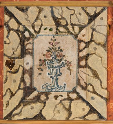 Zdjęcie nr 57: Umeblowanie zakrystii usytuowane jest wzdłuż ścian północnej, południowej i wschodniej pomieszczenia.  Na ścianie północnej, w części dolnej znajdują się trzy połączone ze sobą komody, każda o czterech szufladach, nakryte jednym blatem. W części górnej mieszczą się pięcioosiowe szafki z szufladami w cokole. Osie artykułowe są pilastrami hermowymi. Na osi środkowej szafka jest nieco wyższa i szersza z drzwiczkami dekorowanymi prostokątną, uszatą, oprofilowaną płyciną z malowanym przedstawieniem Chrystusa Eucharystycznego. Drzwiczki pozostałych szafek mają kształt stojących prostokątów i dekorowane są płycinami o wklęsłych narożach, zdobionymi gałązkami czerwonych róż, ułożonych w rokokowych wazonach. Ścianki zamknięte są niepełnym belkowaniem z gzymsem. W partii zwieńczenia osie artykułowane są cokolikami, na których ustawione są toczone, kuliste wazoniki. Pomiędzy nimi umieszczone są kartusze utworzone z ornamentu małżowinowo-chrząstkowego z malowanymi emblematami na owalnych medalionach, które ułożone są kolejno od lewej strony: 
1. Pionowo ustawiony miecz, ostrzem skierowany ku górze, połączony ze skrzyżowanymi berłem i dwoma kluczami, od których odchodzą fantazyjnie ułożone sznury w kolorze czerwonym. U góry napis na szarfie: „OBEDITE”.
2. W górnej części wyłaniająca się z chmur ręka trzymająca w dłoni węgielnicę i przymocowane do niej na łańcuszku tablice Dekalogu. Napis na szarfie: „OMNIA SVSTINET”.
3. Bóg Ojciec ukazany w półpostaci, lewą ręką opiera się na kuli ziemskiej, prawą czyni gest błogosławieństwa. 
4. Bujnie ulistnione, ciemnozielone drzewko spięte w dolnej części złotą formą w kształcie dwóch wywiniętych wolutek. Napis na szarfie: „GAVDET PATIENTIA DVRIS”. 
5. W górnej części obrazu z chmur wyłania się ręka, która zrzuca na ziemię iskrzący pocisk i dwa skrzyżowane pioruny, połączone parą białych skrzydeł. Napis „FORTIS VLTOR”.
 
Na ścianie środkowej, wschodniej znajduje się sarkofagowa mensa, powyżej parawanowa ścianka na profilowanym cokole, artykułowana pilastrami, pomiędzy którymi umieszczone są płyciny z kształcie leżących prostokątów z obrazami; ścianka zamknięta jest profilowanym gzymsem. W zwieńczeniu, na jej skrajach znajdują się owalne medaliony ujęte w kartusze z ornamentu małżowinowo-chrząstkowego. W medalionie po lewej stronie namalowane są litery alfa i omega na błękitnym tle oraz wstęga z napisem: „RENOVATUM A(NNO) D(OMINI) 1975”. Po prawej stronie analogiczny kartusz z literami w medalionie: „Ω / O / N” wpisane w formę krzyża, otoczonego niepełną aureolą; powyżej wstęga z napisem: „VIDENTEM AUDERE”. W płycinach obrazy przedstawiają świętych w ujęciu do pasa, zwróconych ku środkowi; od lewej:
1. Święty Demetriusz z włócznią opartą o prawy bark, ubrany w habit zakonu kanoników laterańskich od pokuty.
2. Święty Klet z aniołkiem, który trzyma w dłoni palmę męczeństwa i krzyż papieski. W prawym górnym narożu obrazu napis: „FAC HVIC SIGNO HONOREM”.
3. Święty Augustyn z gorejącym sercem na piersi i aniołkiem z łyżką i miseczką w dłoniach.
4. Święty ubrany w habit Marków, który trzyma w dłoni serce z krzyżem, podtrzymywane przez Chrystusa na obłokach – prawdopodobnie św. Cyriak, założyciel zakonu.
 
Na ścianie południowej znajduje się analogiczne umeblowanie, jak na ścianie północnej. W dolnej części dwie komody, a w miejscu trzeciej od wschodu szafka zdobiona dwiema uszatymi płycinami. Górna część mebla w przeciwieństwie do ściany północnej bez podwyższenia części środkowej. 
Na ścianie południowej:
1. Jasnobrązowa harfa na błękitnym tle i napis: „IN DOMINO”.
2. Ciemnobrązowy ptak i trzy podrywające się do lotu młode, w górnej części złote słońce i napis: „NON QUAE SVPER TERRAM.”
3. Po lewej stronie kompozycji wyłaniająca się z chmur ręka trzymająca skrzyżowane: miecz, czerwony krzyż i palmę. Napis: „NON ERVBESCO”.
4. W centrum przedstawienia krzak białej lilii o trzech rozgałęzieniach, w tle chmury w odcieniach koloru szaroniebieskiego. Napis na szarfie: „PER ARDVA DVLCIS”.
5. W lewej części kompozycji uskrzydlony jeleń, wspięty na tylnych nogach, po prawej stronie czarne i brązowe skały, w partii górnej otwarta korona, umieszczona pośrodku obłoku obwiedzionego biało-czerwonym pasem. Napis: „ET COMPREHENDATIS”.
 
W miejscu połączenia komód ścian północnej i południowej z dolną częścią konstrukcji na ścianie wschodniej znajdują się ukośnie ustawione, jednoskrzydłowe szafki o drzwiczkach dekorowanych prostokątną płyciną o wklęsłych narożach. Ścianki boczne części północnej i południowej zdobione są ukośną kratką. Powierzchnia szafek i komód pokryta jest polichromią imitującą marmur w kolorze beżowym, szarokremowym, różowym i rdzawym. Blaty malowane są farbą olejną w kolorze beżowym. Obramienia medalionów malowane w kolorze rdzawozłotym. Tło w większości medalionów w odcieniach błękitu, w górnych częściach majuskułowe napisy objaśniające przedstawienie, umieszczone w białych i półkoliście ułożonych szarfach. 