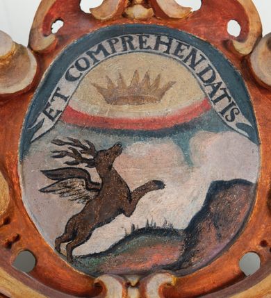 Zdjęcie nr 90: Umeblowanie zakrystii usytuowane jest wzdłuż ścian północnej, południowej i wschodniej pomieszczenia.  Na ścianie północnej, w części dolnej znajdują się trzy połączone ze sobą komody, każda o czterech szufladach, nakryte jednym blatem. W części górnej mieszczą się pięcioosiowe szafki z szufladami w cokole. Osie artykułowe są pilastrami hermowymi. Na osi środkowej szafka jest nieco wyższa i szersza z drzwiczkami dekorowanymi prostokątną, uszatą, oprofilowaną płyciną z malowanym przedstawieniem Chrystusa Eucharystycznego. Drzwiczki pozostałych szafek mają kształt stojących prostokątów i dekorowane są płycinami o wklęsłych narożach, zdobionymi gałązkami czerwonych róż, ułożonych w rokokowych wazonach. Ścianki zamknięte są niepełnym belkowaniem z gzymsem. W partii zwieńczenia osie artykułowane są cokolikami, na których ustawione są toczone, kuliste wazoniki. Pomiędzy nimi umieszczone są kartusze utworzone z ornamentu małżowinowo-chrząstkowego z malowanymi emblematami na owalnych medalionach, które ułożone są kolejno od lewej strony: 
1. Pionowo ustawiony miecz, ostrzem skierowany ku górze, połączony ze skrzyżowanymi berłem i dwoma kluczami, od których odchodzą fantazyjnie ułożone sznury w kolorze czerwonym. U góry napis na szarfie: „OBEDITE”.
2. W górnej części wyłaniająca się z chmur ręka trzymająca w dłoni węgielnicę i przymocowane do niej na łańcuszku tablice Dekalogu. Napis na szarfie: „OMNIA SVSTINET”.
3. Bóg Ojciec ukazany w półpostaci, lewą ręką opiera się na kuli ziemskiej, prawą czyni gest błogosławieństwa. 
4. Bujnie ulistnione, ciemnozielone drzewko spięte w dolnej części złotą formą w kształcie dwóch wywiniętych wolutek. Napis na szarfie: „GAVDET PATIENTIA DVRIS”. 
5. W górnej części obrazu z chmur wyłania się ręka, która zrzuca na ziemię iskrzący pocisk i dwa skrzyżowane pioruny, połączone parą białych skrzydeł. Napis „FORTIS VLTOR”.
 
Na ścianie środkowej, wschodniej znajduje się sarkofagowa mensa, powyżej parawanowa ścianka na profilowanym cokole, artykułowana pilastrami, pomiędzy którymi umieszczone są płyciny z kształcie leżących prostokątów z obrazami; ścianka zamknięta jest profilowanym gzymsem. W zwieńczeniu, na jej skrajach znajdują się owalne medaliony ujęte w kartusze z ornamentu małżowinowo-chrząstkowego. W medalionie po lewej stronie namalowane są litery alfa i omega na błękitnym tle oraz wstęga z napisem: „RENOVATUM A(NNO) D(OMINI) 1975”. Po prawej stronie analogiczny kartusz z literami w medalionie: „Ω / O / N” wpisane w formę krzyża, otoczonego niepełną aureolą; powyżej wstęga z napisem: „VIDENTEM AUDERE”. W płycinach obrazy przedstawiają świętych w ujęciu do pasa, zwróconych ku środkowi; od lewej:
1. Święty Demetriusz z włócznią opartą o prawy bark, ubrany w habit zakonu kanoników laterańskich od pokuty.
2. Święty Klet z aniołkiem, który trzyma w dłoni palmę męczeństwa i krzyż papieski. W prawym górnym narożu obrazu napis: „FAC HVIC SIGNO HONOREM”.
3. Święty Augustyn z gorejącym sercem na piersi i aniołkiem z łyżką i miseczką w dłoniach.
4. Święty ubrany w habit Marków, który trzyma w dłoni serce z krzyżem, podtrzymywane przez Chrystusa na obłokach – prawdopodobnie św. Cyriak, założyciel zakonu.
 
Na ścianie południowej znajduje się analogiczne umeblowanie, jak na ścianie północnej. W dolnej części dwie komody, a w miejscu trzeciej od wschodu szafka zdobiona dwiema uszatymi płycinami. Górna część mebla w przeciwieństwie do ściany północnej bez podwyższenia części środkowej. 
Na ścianie południowej:
1. Jasnobrązowa harfa na błękitnym tle i napis: „IN DOMINO”.
2. Ciemnobrązowy ptak i trzy podrywające się do lotu młode, w górnej części złote słońce i napis: „NON QUAE SVPER TERRAM.”
3. Po lewej stronie kompozycji wyłaniająca się z chmur ręka trzymająca skrzyżowane: miecz, czerwony krzyż i palmę. Napis: „NON ERVBESCO”.
4. W centrum przedstawienia krzak białej lilii o trzech rozgałęzieniach, w tle chmury w odcieniach koloru szaroniebieskiego. Napis na szarfie: „PER ARDVA DVLCIS”.
5. W lewej części kompozycji uskrzydlony jeleń, wspięty na tylnych nogach, po prawej stronie czarne i brązowe skały, w partii górnej otwarta korona, umieszczona pośrodku obłoku obwiedzionego biało-czerwonym pasem. Napis: „ET COMPREHENDATIS”.
 
W miejscu połączenia komód ścian północnej i południowej z dolną częścią konstrukcji na ścianie wschodniej znajdują się ukośnie ustawione, jednoskrzydłowe szafki o drzwiczkach dekorowanych prostokątną płyciną o wklęsłych narożach. Ścianki boczne części północnej i południowej zdobione są ukośną kratką. Powierzchnia szafek i komód pokryta jest polichromią imitującą marmur w kolorze beżowym, szarokremowym, różowym i rdzawym. Blaty malowane są farbą olejną w kolorze beżowym. Obramienia medalionów malowane w kolorze rdzawozłotym. Tło w większości medalionów w odcieniach błękitu, w górnych częściach majuskułowe napisy objaśniające przedstawienie, umieszczone w białych i półkoliście ułożonych szarfach. 