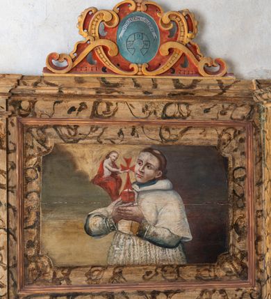 Zdjęcie nr 105: Umeblowanie zakrystii usytuowane jest wzdłuż ścian północnej, południowej i wschodniej pomieszczenia.  Na ścianie północnej, w części dolnej znajdują się trzy połączone ze sobą komody, każda o czterech szufladach, nakryte jednym blatem. W części górnej mieszczą się pięcioosiowe szafki z szufladami w cokole. Osie artykułowe są pilastrami hermowymi. Na osi środkowej szafka jest nieco wyższa i szersza z drzwiczkami dekorowanymi prostokątną, uszatą, oprofilowaną płyciną z malowanym przedstawieniem Chrystusa Eucharystycznego. Drzwiczki pozostałych szafek mają kształt stojących prostokątów i dekorowane są płycinami o wklęsłych narożach, zdobionymi gałązkami czerwonych róż, ułożonych w rokokowych wazonach. Ścianki zamknięte są niepełnym belkowaniem z gzymsem. W partii zwieńczenia osie artykułowane są cokolikami, na których ustawione są toczone, kuliste wazoniki. Pomiędzy nimi umieszczone są kartusze utworzone z ornamentu małżowinowo-chrząstkowego z malowanymi emblematami na owalnych medalionach, które ułożone są kolejno od lewej strony: 
1. Pionowo ustawiony miecz, ostrzem skierowany ku górze, połączony ze skrzyżowanymi berłem i dwoma kluczami, od których odchodzą fantazyjnie ułożone sznury w kolorze czerwonym. U góry napis na szarfie: „OBEDITE”.
2. W górnej części wyłaniająca się z chmur ręka trzymająca w dłoni węgielnicę i przymocowane do niej na łańcuszku tablice Dekalogu. Napis na szarfie: „OMNIA SVSTINET”.
3. Bóg Ojciec ukazany w półpostaci, lewą ręką opiera się na kuli ziemskiej, prawą czyni gest błogosławieństwa. 
4. Bujnie ulistnione, ciemnozielone drzewko spięte w dolnej części złotą formą w kształcie dwóch wywiniętych wolutek. Napis na szarfie: „GAVDET PATIENTIA DVRIS”. 
5. W górnej części obrazu z chmur wyłania się ręka, która zrzuca na ziemię iskrzący pocisk i dwa skrzyżowane pioruny, połączone parą białych skrzydeł. Napis „FORTIS VLTOR”.
 
Na ścianie środkowej, wschodniej znajduje się sarkofagowa mensa, powyżej parawanowa ścianka na profilowanym cokole, artykułowana pilastrami, pomiędzy którymi umieszczone są płyciny z kształcie leżących prostokątów z obrazami; ścianka zamknięta jest profilowanym gzymsem. W zwieńczeniu, na jej skrajach znajdują się owalne medaliony ujęte w kartusze z ornamentu małżowinowo-chrząstkowego. W medalionie po lewej stronie namalowane są litery alfa i omega na błękitnym tle oraz wstęga z napisem: „RENOVATUM A(NNO) D(OMINI) 1975”. Po prawej stronie analogiczny kartusz z literami w medalionie: „Ω / O / N” wpisane w formę krzyża, otoczonego niepełną aureolą; powyżej wstęga z napisem: „VIDENTEM AUDERE”. W płycinach obrazy przedstawiają świętych w ujęciu do pasa, zwróconych ku środkowi; od lewej:
1. Święty Demetriusz z włócznią opartą o prawy bark, ubrany w habit zakonu kanoników laterańskich od pokuty.
2. Święty Klet z aniołkiem, który trzyma w dłoni palmę męczeństwa i krzyż papieski. W prawym górnym narożu obrazu napis: „FAC HVIC SIGNO HONOREM”.
3. Święty Augustyn z gorejącym sercem na piersi i aniołkiem z łyżką i miseczką w dłoniach.
4. Święty ubrany w habit Marków, który trzyma w dłoni serce z krzyżem, podtrzymywane przez Chrystusa na obłokach – prawdopodobnie św. Cyriak, założyciel zakonu.
 
Na ścianie południowej znajduje się analogiczne umeblowanie, jak na ścianie północnej. W dolnej części dwie komody, a w miejscu trzeciej od wschodu szafka zdobiona dwiema uszatymi płycinami. Górna część mebla w przeciwieństwie do ściany północnej bez podwyższenia części środkowej. 
Na ścianie południowej:
1. Jasnobrązowa harfa na błękitnym tle i napis: „IN DOMINO”.
2. Ciemnobrązowy ptak i trzy podrywające się do lotu młode, w górnej części złote słońce i napis: „NON QUAE SVPER TERRAM.”
3. Po lewej stronie kompozycji wyłaniająca się z chmur ręka trzymająca skrzyżowane: miecz, czerwony krzyż i palmę. Napis: „NON ERVBESCO”.
4. W centrum przedstawienia krzak białej lilii o trzech rozgałęzieniach, w tle chmury w odcieniach koloru szaroniebieskiego. Napis na szarfie: „PER ARDVA DVLCIS”.
5. W lewej części kompozycji uskrzydlony jeleń, wspięty na tylnych nogach, po prawej stronie czarne i brązowe skały, w partii górnej otwarta korona, umieszczona pośrodku obłoku obwiedzionego biało-czerwonym pasem. Napis: „ET COMPREHENDATIS”.
 
W miejscu połączenia komód ścian północnej i południowej z dolną częścią konstrukcji na ścianie wschodniej znajdują się ukośnie ustawione, jednoskrzydłowe szafki o drzwiczkach dekorowanych prostokątną płyciną o wklęsłych narożach. Ścianki boczne części północnej i południowej zdobione są ukośną kratką. Powierzchnia szafek i komód pokryta jest polichromią imitującą marmur w kolorze beżowym, szarokremowym, różowym i rdzawym. Blaty malowane są farbą olejną w kolorze beżowym. Obramienia medalionów malowane w kolorze rdzawozłotym. Tło w większości medalionów w odcieniach błękitu, w górnych częściach majuskułowe napisy objaśniające przedstawienie, umieszczone w białych i półkoliście ułożonych szarfach. 