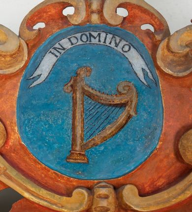 Zdjęcie nr 106: Umeblowanie zakrystii usytuowane jest wzdłuż ścian północnej, południowej i wschodniej pomieszczenia.  Na ścianie północnej, w części dolnej znajdują się trzy połączone ze sobą komody, każda o czterech szufladach, nakryte jednym blatem. W części górnej mieszczą się pięcioosiowe szafki z szufladami w cokole. Osie artykułowe są pilastrami hermowymi. Na osi środkowej szafka jest nieco wyższa i szersza z drzwiczkami dekorowanymi prostokątną, uszatą, oprofilowaną płyciną z malowanym przedstawieniem Chrystusa Eucharystycznego. Drzwiczki pozostałych szafek mają kształt stojących prostokątów i dekorowane są płycinami o wklęsłych narożach, zdobionymi gałązkami czerwonych róż, ułożonych w rokokowych wazonach. Ścianki zamknięte są niepełnym belkowaniem z gzymsem. W partii zwieńczenia osie artykułowane są cokolikami, na których ustawione są toczone, kuliste wazoniki. Pomiędzy nimi umieszczone są kartusze utworzone z ornamentu małżowinowo-chrząstkowego z malowanymi emblematami na owalnych medalionach, które ułożone są kolejno od lewej strony: 
1. Pionowo ustawiony miecz, ostrzem skierowany ku górze, połączony ze skrzyżowanymi berłem i dwoma kluczami, od których odchodzą fantazyjnie ułożone sznury w kolorze czerwonym. U góry napis na szarfie: „OBEDITE”.
2. W górnej części wyłaniająca się z chmur ręka trzymająca w dłoni węgielnicę i przymocowane do niej na łańcuszku tablice Dekalogu. Napis na szarfie: „OMNIA SVSTINET”.
3. Bóg Ojciec ukazany w półpostaci, lewą ręką opiera się na kuli ziemskiej, prawą czyni gest błogosławieństwa. 
4. Bujnie ulistnione, ciemnozielone drzewko spięte w dolnej części złotą formą w kształcie dwóch wywiniętych wolutek. Napis na szarfie: „GAVDET PATIENTIA DVRIS”. 
5. W górnej części obrazu z chmur wyłania się ręka, która zrzuca na ziemię iskrzący pocisk i dwa skrzyżowane pioruny, połączone parą białych skrzydeł. Napis „FORTIS VLTOR”.
 
Na ścianie środkowej, wschodniej znajduje się sarkofagowa mensa, powyżej parawanowa ścianka na profilowanym cokole, artykułowana pilastrami, pomiędzy którymi umieszczone są płyciny z kształcie leżących prostokątów z obrazami; ścianka zamknięta jest profilowanym gzymsem. W zwieńczeniu, na jej skrajach znajdują się owalne medaliony ujęte w kartusze z ornamentu małżowinowo-chrząstkowego. W medalionie po lewej stronie namalowane są litery alfa i omega na błękitnym tle oraz wstęga z napisem: „RENOVATUM A(NNO) D(OMINI) 1975”. Po prawej stronie analogiczny kartusz z literami w medalionie: „Ω / O / N” wpisane w formę krzyża, otoczonego niepełną aureolą; powyżej wstęga z napisem: „VIDENTEM AUDERE”. W płycinach obrazy przedstawiają świętych w ujęciu do pasa, zwróconych ku środkowi; od lewej:
1. Święty Demetriusz z włócznią opartą o prawy bark, ubrany w habit zakonu kanoników laterańskich od pokuty.
2. Święty Klet z aniołkiem, który trzyma w dłoni palmę męczeństwa i krzyż papieski. W prawym górnym narożu obrazu napis: „FAC HVIC SIGNO HONOREM”.
3. Święty Augustyn z gorejącym sercem na piersi i aniołkiem z łyżką i miseczką w dłoniach.
4. Święty ubrany w habit Marków, który trzyma w dłoni serce z krzyżem, podtrzymywane przez Chrystusa na obłokach – prawdopodobnie św. Cyriak, założyciel zakonu.
 
Na ścianie południowej znajduje się analogiczne umeblowanie, jak na ścianie północnej. W dolnej części dwie komody, a w miejscu trzeciej od wschodu szafka zdobiona dwiema uszatymi płycinami. Górna część mebla w przeciwieństwie do ściany północnej bez podwyższenia części środkowej. 
Na ścianie południowej:
1. Jasnobrązowa harfa na błękitnym tle i napis: „IN DOMINO”.
2. Ciemnobrązowy ptak i trzy podrywające się do lotu młode, w górnej części złote słońce i napis: „NON QUAE SVPER TERRAM.”
3. Po lewej stronie kompozycji wyłaniająca się z chmur ręka trzymająca skrzyżowane: miecz, czerwony krzyż i palmę. Napis: „NON ERVBESCO”.
4. W centrum przedstawienia krzak białej lilii o trzech rozgałęzieniach, w tle chmury w odcieniach koloru szaroniebieskiego. Napis na szarfie: „PER ARDVA DVLCIS”.
5. W lewej części kompozycji uskrzydlony jeleń, wspięty na tylnych nogach, po prawej stronie czarne i brązowe skały, w partii górnej otwarta korona, umieszczona pośrodku obłoku obwiedzionego biało-czerwonym pasem. Napis: „ET COMPREHENDATIS”.
 
W miejscu połączenia komód ścian północnej i południowej z dolną częścią konstrukcji na ścianie wschodniej znajdują się ukośnie ustawione, jednoskrzydłowe szafki o drzwiczkach dekorowanych prostokątną płyciną o wklęsłych narożach. Ścianki boczne części północnej i południowej zdobione są ukośną kratką. Powierzchnia szafek i komód pokryta jest polichromią imitującą marmur w kolorze beżowym, szarokremowym, różowym i rdzawym. Blaty malowane są farbą olejną w kolorze beżowym. Obramienia medalionów malowane w kolorze rdzawozłotym. Tło w większości medalionów w odcieniach błękitu, w górnych częściach majuskułowe napisy objaśniające przedstawienie, umieszczone w białych i półkoliście ułożonych szarfach. 