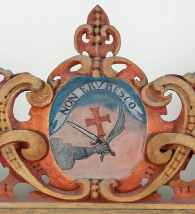 Zdjęcie nr 119: Umeblowanie zakrystii usytuowane jest wzdłuż ścian północnej, południowej i wschodniej pomieszczenia.  Na ścianie północnej, w części dolnej znajdują się trzy połączone ze sobą komody, każda o czterech szufladach, nakryte jednym blatem. W części górnej mieszczą się pięcioosiowe szafki z szufladami w cokole. Osie artykułowe są pilastrami hermowymi. Na osi środkowej szafka jest nieco wyższa i szersza z drzwiczkami dekorowanymi prostokątną, uszatą, oprofilowaną płyciną z malowanym przedstawieniem Chrystusa Eucharystycznego. Drzwiczki pozostałych szafek mają kształt stojących prostokątów i dekorowane są płycinami o wklęsłych narożach, zdobionymi gałązkami czerwonych róż, ułożonych w rokokowych wazonach. Ścianki zamknięte są niepełnym belkowaniem z gzymsem. W partii zwieńczenia osie artykułowane są cokolikami, na których ustawione są toczone, kuliste wazoniki. Pomiędzy nimi umieszczone są kartusze utworzone z ornamentu małżowinowo-chrząstkowego z malowanymi emblematami na owalnych medalionach, które ułożone są kolejno od lewej strony: 
1. Pionowo ustawiony miecz, ostrzem skierowany ku górze, połączony ze skrzyżowanymi berłem i dwoma kluczami, od których odchodzą fantazyjnie ułożone sznury w kolorze czerwonym. U góry napis na szarfie: „OBEDITE”.
2. W górnej części wyłaniająca się z chmur ręka trzymająca w dłoni węgielnicę i przymocowane do niej na łańcuszku tablice Dekalogu. Napis na szarfie: „OMNIA SVSTINET”.
3. Bóg Ojciec ukazany w półpostaci, lewą ręką opiera się na kuli ziemskiej, prawą czyni gest błogosławieństwa. 
4. Bujnie ulistnione, ciemnozielone drzewko spięte w dolnej części złotą formą w kształcie dwóch wywiniętych wolutek. Napis na szarfie: „GAVDET PATIENTIA DVRIS”. 
5. W górnej części obrazu z chmur wyłania się ręka, która zrzuca na ziemię iskrzący pocisk i dwa skrzyżowane pioruny, połączone parą białych skrzydeł. Napis „FORTIS VLTOR”.
 
Na ścianie środkowej, wschodniej znajduje się sarkofagowa mensa, powyżej parawanowa ścianka na profilowanym cokole, artykułowana pilastrami, pomiędzy którymi umieszczone są płyciny z kształcie leżących prostokątów z obrazami; ścianka zamknięta jest profilowanym gzymsem. W zwieńczeniu, na jej skrajach znajdują się owalne medaliony ujęte w kartusze z ornamentu małżowinowo-chrząstkowego. W medalionie po lewej stronie namalowane są litery alfa i omega na błękitnym tle oraz wstęga z napisem: „RENOVATUM A(NNO) D(OMINI) 1975”. Po prawej stronie analogiczny kartusz z literami w medalionie: „Ω / O / N” wpisane w formę krzyża, otoczonego niepełną aureolą; powyżej wstęga z napisem: „VIDENTEM AUDERE”. W płycinach obrazy przedstawiają świętych w ujęciu do pasa, zwróconych ku środkowi; od lewej:
1. Święty Demetriusz z włócznią opartą o prawy bark, ubrany w habit zakonu kanoników laterańskich od pokuty.
2. Święty Klet z aniołkiem, który trzyma w dłoni palmę męczeństwa i krzyż papieski. W prawym górnym narożu obrazu napis: „FAC HVIC SIGNO HONOREM”.
3. Święty Augustyn z gorejącym sercem na piersi i aniołkiem z łyżką i miseczką w dłoniach.
4. Święty ubrany w habit Marków, który trzyma w dłoni serce z krzyżem, podtrzymywane przez Chrystusa na obłokach – prawdopodobnie św. Cyriak, założyciel zakonu.
 
Na ścianie południowej znajduje się analogiczne umeblowanie, jak na ścianie północnej. W dolnej części dwie komody, a w miejscu trzeciej od wschodu szafka zdobiona dwiema uszatymi płycinami. Górna część mebla w przeciwieństwie do ściany północnej bez podwyższenia części środkowej. 
Na ścianie południowej:
1. Jasnobrązowa harfa na błękitnym tle i napis: „IN DOMINO”.
2. Ciemnobrązowy ptak i trzy podrywające się do lotu młode, w górnej części złote słońce i napis: „NON QUAE SVPER TERRAM.”
3. Po lewej stronie kompozycji wyłaniająca się z chmur ręka trzymająca skrzyżowane: miecz, czerwony krzyż i palmę. Napis: „NON ERVBESCO”.
4. W centrum przedstawienia krzak białej lilii o trzech rozgałęzieniach, w tle chmury w odcieniach koloru szaroniebieskiego. Napis na szarfie: „PER ARDVA DVLCIS”.
5. W lewej części kompozycji uskrzydlony jeleń, wspięty na tylnych nogach, po prawej stronie czarne i brązowe skały, w partii górnej otwarta korona, umieszczona pośrodku obłoku obwiedzionego biało-czerwonym pasem. Napis: „ET COMPREHENDATIS”.
 
W miejscu połączenia komód ścian północnej i południowej z dolną częścią konstrukcji na ścianie wschodniej znajdują się ukośnie ustawione, jednoskrzydłowe szafki o drzwiczkach dekorowanych prostokątną płyciną o wklęsłych narożach. Ścianki boczne części północnej i południowej zdobione są ukośną kratką. Powierzchnia szafek i komód pokryta jest polichromią imitującą marmur w kolorze beżowym, szarokremowym, różowym i rdzawym. Blaty malowane są farbą olejną w kolorze beżowym. Obramienia medalionów malowane w kolorze rdzawozłotym. Tło w większości medalionów w odcieniach błękitu, w górnych częściach majuskułowe napisy objaśniające przedstawienie, umieszczone w białych i półkoliście ułożonych szarfach. 