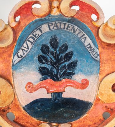 Zdjęcie nr 130: Umeblowanie zakrystii usytuowane jest wzdłuż ścian północnej, południowej i wschodniej pomieszczenia.  Na ścianie północnej, w części dolnej znajdują się trzy połączone ze sobą komody, każda o czterech szufladach, nakryte jednym blatem. W części górnej mieszczą się pięcioosiowe szafki z szufladami w cokole. Osie artykułowe są pilastrami hermowymi. Na osi środkowej szafka jest nieco wyższa i szersza z drzwiczkami dekorowanymi prostokątną, uszatą, oprofilowaną płyciną z malowanym przedstawieniem Chrystusa Eucharystycznego. Drzwiczki pozostałych szafek mają kształt stojących prostokątów i dekorowane są płycinami o wklęsłych narożach, zdobionymi gałązkami czerwonych róż, ułożonych w rokokowych wazonach. Ścianki zamknięte są niepełnym belkowaniem z gzymsem. W partii zwieńczenia osie artykułowane są cokolikami, na których ustawione są toczone, kuliste wazoniki. Pomiędzy nimi umieszczone są kartusze utworzone z ornamentu małżowinowo-chrząstkowego z malowanymi emblematami na owalnych medalionach, które ułożone są kolejno od lewej strony: 
1. Pionowo ustawiony miecz, ostrzem skierowany ku górze, połączony ze skrzyżowanymi berłem i dwoma kluczami, od których odchodzą fantazyjnie ułożone sznury w kolorze czerwonym. U góry napis na szarfie: „OBEDITE”.
2. W górnej części wyłaniająca się z chmur ręka trzymająca w dłoni węgielnicę i przymocowane do niej na łańcuszku tablice Dekalogu. Napis na szarfie: „OMNIA SVSTINET”.
3. Bóg Ojciec ukazany w półpostaci, lewą ręką opiera się na kuli ziemskiej, prawą czyni gest błogosławieństwa. 
4. Bujnie ulistnione, ciemnozielone drzewko spięte w dolnej części złotą formą w kształcie dwóch wywiniętych wolutek. Napis na szarfie: „GAVDET PATIENTIA DVRIS”. 
5. W górnej części obrazu z chmur wyłania się ręka, która zrzuca na ziemię iskrzący pocisk i dwa skrzyżowane pioruny, połączone parą białych skrzydeł. Napis „FORTIS VLTOR”.
 
Na ścianie środkowej, wschodniej znajduje się sarkofagowa mensa, powyżej parawanowa ścianka na profilowanym cokole, artykułowana pilastrami, pomiędzy którymi umieszczone są płyciny z kształcie leżących prostokątów z obrazami; ścianka zamknięta jest profilowanym gzymsem. W zwieńczeniu, na jej skrajach znajdują się owalne medaliony ujęte w kartusze z ornamentu małżowinowo-chrząstkowego. W medalionie po lewej stronie namalowane są litery alfa i omega na błękitnym tle oraz wstęga z napisem: „RENOVATUM A(NNO) D(OMINI) 1975”. Po prawej stronie analogiczny kartusz z literami w medalionie: „Ω / O / N” wpisane w formę krzyża, otoczonego niepełną aureolą; powyżej wstęga z napisem: „VIDENTEM AUDERE”. W płycinach obrazy przedstawiają świętych w ujęciu do pasa, zwróconych ku środkowi; od lewej:
1. Święty Demetriusz z włócznią opartą o prawy bark, ubrany w habit zakonu kanoników laterańskich od pokuty.
2. Święty Klet z aniołkiem, który trzyma w dłoni palmę męczeństwa i krzyż papieski. W prawym górnym narożu obrazu napis: „FAC HVIC SIGNO HONOREM”.
3. Święty Augustyn z gorejącym sercem na piersi i aniołkiem z łyżką i miseczką w dłoniach.
4. Święty ubrany w habit Marków, który trzyma w dłoni serce z krzyżem, podtrzymywane przez Chrystusa na obłokach – prawdopodobnie św. Cyriak, założyciel zakonu.
 
Na ścianie południowej znajduje się analogiczne umeblowanie, jak na ścianie północnej. W dolnej części dwie komody, a w miejscu trzeciej od wschodu szafka zdobiona dwiema uszatymi płycinami. Górna część mebla w przeciwieństwie do ściany północnej bez podwyższenia części środkowej. 
Na ścianie południowej:
1. Jasnobrązowa harfa na błękitnym tle i napis: „IN DOMINO”.
2. Ciemnobrązowy ptak i trzy podrywające się do lotu młode, w górnej części złote słońce i napis: „NON QUAE SVPER TERRAM.”
3. Po lewej stronie kompozycji wyłaniająca się z chmur ręka trzymająca skrzyżowane: miecz, czerwony krzyż i palmę. Napis: „NON ERVBESCO”.
4. W centrum przedstawienia krzak białej lilii o trzech rozgałęzieniach, w tle chmury w odcieniach koloru szaroniebieskiego. Napis na szarfie: „PER ARDVA DVLCIS”.
5. W lewej części kompozycji uskrzydlony jeleń, wspięty na tylnych nogach, po prawej stronie czarne i brązowe skały, w partii górnej otwarta korona, umieszczona pośrodku obłoku obwiedzionego biało-czerwonym pasem. Napis: „ET COMPREHENDATIS”.
 
W miejscu połączenia komód ścian północnej i południowej z dolną częścią konstrukcji na ścianie wschodniej znajdują się ukośnie ustawione, jednoskrzydłowe szafki o drzwiczkach dekorowanych prostokątną płyciną o wklęsłych narożach. Ścianki boczne części północnej i południowej zdobione są ukośną kratką. Powierzchnia szafek i komód pokryta jest polichromią imitującą marmur w kolorze beżowym, szarokremowym, różowym i rdzawym. Blaty malowane są farbą olejną w kolorze beżowym. Obramienia medalionów malowane w kolorze rdzawozłotym. Tło w większości medalionów w odcieniach błękitu, w górnych częściach majuskułowe napisy objaśniające przedstawienie, umieszczone w białych i półkoliście ułożonych szarfach. 