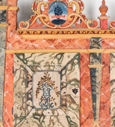 Zdjęcie nr 8: Umeblowanie zakrystii usytuowane jest wzdłuż ścian północnej, południowej i wschodniej pomieszczenia.  Na ścianie północnej, w części dolnej znajdują się trzy połączone ze sobą komody, każda o czterech szufladach, nakryte jednym blatem. W części górnej mieszczą się pięcioosiowe szafki z szufladami w cokole. Osie artykułowe są pilastrami hermowymi. Na osi środkowej szafka jest nieco wyższa i szersza z drzwiczkami dekorowanymi prostokątną, uszatą, oprofilowaną płyciną z malowanym przedstawieniem Chrystusa Eucharystycznego. Drzwiczki pozostałych szafek mają kształt stojących prostokątów i dekorowane są płycinami o wklęsłych narożach, zdobionymi gałązkami czerwonych róż, ułożonych w rokokowych wazonach. Ścianki zamknięte są niepełnym belkowaniem z gzymsem. W partii zwieńczenia osie artykułowane są cokolikami, na których ustawione są toczone, kuliste wazoniki. Pomiędzy nimi umieszczone są kartusze utworzone z ornamentu małżowinowo-chrząstkowego z malowanymi emblematami na owalnych medalionach, które ułożone są kolejno od lewej strony: 
1. Pionowo ustawiony miecz, ostrzem skierowany ku górze, połączony ze skrzyżowanymi berłem i dwoma kluczami, od których odchodzą fantazyjnie ułożone sznury w kolorze czerwonym. U góry napis na szarfie: „OBEDITE”.
2. W górnej części wyłaniająca się z chmur ręka trzymająca w dłoni węgielnicę i przymocowane do niej na łańcuszku tablice Dekalogu. Napis na szarfie: „OMNIA SVSTINET”.
3. Bóg Ojciec ukazany w półpostaci, lewą ręką opiera się na kuli ziemskiej, prawą czyni gest błogosławieństwa. 
4. Bujnie ulistnione, ciemnozielone drzewko spięte w dolnej części złotą formą w kształcie dwóch wywiniętych wolutek. Napis na szarfie: „GAVDET PATIENTIA DVRIS”. 
5. W górnej części obrazu z chmur wyłania się ręka, która zrzuca na ziemię iskrzący pocisk i dwa skrzyżowane pioruny, połączone parą białych skrzydeł. Napis „FORTIS VLTOR”.
 
Na ścianie środkowej, wschodniej znajduje się sarkofagowa mensa, powyżej parawanowa ścianka na profilowanym cokole, artykułowana pilastrami, pomiędzy którymi umieszczone są płyciny z kształcie leżących prostokątów z obrazami; ścianka zamknięta jest profilowanym gzymsem. W zwieńczeniu, na jej skrajach znajdują się owalne medaliony ujęte w kartusze z ornamentu małżowinowo-chrząstkowego. W medalionie po lewej stronie namalowane są litery alfa i omega na błękitnym tle oraz wstęga z napisem: „RENOVATUM A(NNO) D(OMINI) 1975”. Po prawej stronie analogiczny kartusz z literami w medalionie: „Ω / O / N” wpisane w formę krzyża, otoczonego niepełną aureolą; powyżej wstęga z napisem: „VIDENTEM AUDERE”. W płycinach obrazy przedstawiają świętych w ujęciu do pasa, zwróconych ku środkowi; od lewej:
1. Święty Demetriusz z włócznią opartą o prawy bark, ubrany w habit zakonu kanoników laterańskich od pokuty.
2. Święty Klet z aniołkiem, który trzyma w dłoni palmę męczeństwa i krzyż papieski. W prawym górnym narożu obrazu napis: „FAC HVIC SIGNO HONOREM”.
3. Święty Augustyn z gorejącym sercem na piersi i aniołkiem z łyżką i miseczką w dłoniach.
4. Święty ubrany w habit Marków, który trzyma w dłoni serce z krzyżem, podtrzymywane przez Chrystusa na obłokach – prawdopodobnie św. Cyriak, założyciel zakonu.
 
Na ścianie południowej znajduje się analogiczne umeblowanie, jak na ścianie północnej. W dolnej części dwie komody, a w miejscu trzeciej od wschodu szafka zdobiona dwiema uszatymi płycinami. Górna część mebla w przeciwieństwie do ściany północnej bez podwyższenia części środkowej. 
Na ścianie południowej:
1. Jasnobrązowa harfa na błękitnym tle i napis: „IN DOMINO”.
2. Ciemnobrązowy ptak i trzy podrywające się do lotu młode, w górnej części złote słońce i napis: „NON QUAE SVPER TERRAM.”
3. Po lewej stronie kompozycji wyłaniająca się z chmur ręka trzymająca skrzyżowane: miecz, czerwony krzyż i palmę. Napis: „NON ERVBESCO”.
4. W centrum przedstawienia krzak białej lilii o trzech rozgałęzieniach, w tle chmury w odcieniach koloru szaroniebieskiego. Napis na szarfie: „PER ARDVA DVLCIS”.
5. W lewej części kompozycji uskrzydlony jeleń, wspięty na tylnych nogach, po prawej stronie czarne i brązowe skały, w partii górnej otwarta korona, umieszczona pośrodku obłoku obwiedzionego biało-czerwonym pasem. Napis: „ET COMPREHENDATIS”.
 
W miejscu połączenia komód ścian północnej i południowej z dolną częścią konstrukcji na ścianie wschodniej znajdują się ukośnie ustawione, jednoskrzydłowe szafki o drzwiczkach dekorowanych prostokątną płyciną o wklęsłych narożach. Ścianki boczne części północnej i południowej zdobione są ukośną kratką. Powierzchnia szafek i komód pokryta jest polichromią imitującą marmur w kolorze beżowym, szarokremowym, różowym i rdzawym. Blaty malowane są farbą olejną w kolorze beżowym. Obramienia medalionów malowane w kolorze rdzawozłotym. Tło w większości medalionów w odcieniach błękitu, w górnych częściach majuskułowe napisy objaśniające przedstawienie, umieszczone w białych i półkoliście ułożonych szarfach. 