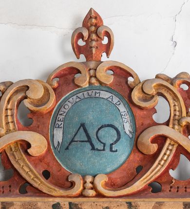 Zdjęcie nr 7: Umeblowanie zakrystii usytuowane jest wzdłuż ścian północnej, południowej i wschodniej pomieszczenia.  Na ścianie północnej, w części dolnej znajdują się trzy połączone ze sobą komody, każda o czterech szufladach, nakryte jednym blatem. W części górnej mieszczą się pięcioosiowe szafki z szufladami w cokole. Osie artykułowe są pilastrami hermowymi. Na osi środkowej szafka jest nieco wyższa i szersza z drzwiczkami dekorowanymi prostokątną, uszatą, oprofilowaną płyciną z malowanym przedstawieniem Chrystusa Eucharystycznego. Drzwiczki pozostałych szafek mają kształt stojących prostokątów i dekorowane są płycinami o wklęsłych narożach, zdobionymi gałązkami czerwonych róż, ułożonych w rokokowych wazonach. Ścianki zamknięte są niepełnym belkowaniem z gzymsem. W partii zwieńczenia osie artykułowane są cokolikami, na których ustawione są toczone, kuliste wazoniki. Pomiędzy nimi umieszczone są kartusze utworzone z ornamentu małżowinowo-chrząstkowego z malowanymi emblematami na owalnych medalionach, które ułożone są kolejno od lewej strony: 
1. Pionowo ustawiony miecz, ostrzem skierowany ku górze, połączony ze skrzyżowanymi berłem i dwoma kluczami, od których odchodzą fantazyjnie ułożone sznury w kolorze czerwonym. U góry napis na szarfie: „OBEDITE”.
2. W górnej części wyłaniająca się z chmur ręka trzymająca w dłoni węgielnicę i przymocowane do niej na łańcuszku tablice Dekalogu. Napis na szarfie: „OMNIA SVSTINET”.
3. Bóg Ojciec ukazany w półpostaci, lewą ręką opiera się na kuli ziemskiej, prawą czyni gest błogosławieństwa. 
4. Bujnie ulistnione, ciemnozielone drzewko spięte w dolnej części złotą formą w kształcie dwóch wywiniętych wolutek. Napis na szarfie: „GAVDET PATIENTIA DVRIS”. 
5. W górnej części obrazu z chmur wyłania się ręka, która zrzuca na ziemię iskrzący pocisk i dwa skrzyżowane pioruny, połączone parą białych skrzydeł. Napis „FORTIS VLTOR”.
 
Na ścianie środkowej, wschodniej znajduje się sarkofagowa mensa, powyżej parawanowa ścianka na profilowanym cokole, artykułowana pilastrami, pomiędzy którymi umieszczone są płyciny z kształcie leżących prostokątów z obrazami; ścianka zamknięta jest profilowanym gzymsem. W zwieńczeniu, na jej skrajach znajdują się owalne medaliony ujęte w kartusze z ornamentu małżowinowo-chrząstkowego. W medalionie po lewej stronie namalowane są litery alfa i omega na błękitnym tle oraz wstęga z napisem: „RENOVATUM A(NNO) D(OMINI) 1975”. Po prawej stronie analogiczny kartusz z literami w medalionie: „Ω / O / N” wpisane w formę krzyża, otoczonego niepełną aureolą; powyżej wstęga z napisem: „VIDENTEM AUDERE”. W płycinach obrazy przedstawiają świętych w ujęciu do pasa, zwróconych ku środkowi; od lewej:
1. Święty Demetriusz z włócznią opartą o prawy bark, ubrany w habit zakonu kanoników laterańskich od pokuty.
2. Święty Klet z aniołkiem, który trzyma w dłoni palmę męczeństwa i krzyż papieski. W prawym górnym narożu obrazu napis: „FAC HVIC SIGNO HONOREM”.
3. Święty Augustyn z gorejącym sercem na piersi i aniołkiem z łyżką i miseczką w dłoniach.
4. Święty ubrany w habit Marków, który trzyma w dłoni serce z krzyżem, podtrzymywane przez Chrystusa na obłokach – prawdopodobnie św. Cyriak, założyciel zakonu.
 
Na ścianie południowej znajduje się analogiczne umeblowanie, jak na ścianie północnej. W dolnej części dwie komody, a w miejscu trzeciej od wschodu szafka zdobiona dwiema uszatymi płycinami. Górna część mebla w przeciwieństwie do ściany północnej bez podwyższenia części środkowej. 
Na ścianie południowej:
1. Jasnobrązowa harfa na błękitnym tle i napis: „IN DOMINO”.
2. Ciemnobrązowy ptak i trzy podrywające się do lotu młode, w górnej części złote słońce i napis: „NON QUAE SVPER TERRAM.”
3. Po lewej stronie kompozycji wyłaniająca się z chmur ręka trzymająca skrzyżowane: miecz, czerwony krzyż i palmę. Napis: „NON ERVBESCO”.
4. W centrum przedstawienia krzak białej lilii o trzech rozgałęzieniach, w tle chmury w odcieniach koloru szaroniebieskiego. Napis na szarfie: „PER ARDVA DVLCIS”.
5. W lewej części kompozycji uskrzydlony jeleń, wspięty na tylnych nogach, po prawej stronie czarne i brązowe skały, w partii górnej otwarta korona, umieszczona pośrodku obłoku obwiedzionego biało-czerwonym pasem. Napis: „ET COMPREHENDATIS”.
 
W miejscu połączenia komód ścian północnej i południowej z dolną częścią konstrukcji na ścianie wschodniej znajdują się ukośnie ustawione, jednoskrzydłowe szafki o drzwiczkach dekorowanych prostokątną płyciną o wklęsłych narożach. Ścianki boczne części północnej i południowej zdobione są ukośną kratką. Powierzchnia szafek i komód pokryta jest polichromią imitującą marmur w kolorze beżowym, szarokremowym, różowym i rdzawym. Blaty malowane są farbą olejną w kolorze beżowym. Obramienia medalionów malowane w kolorze rdzawozłotym. Tło w większości medalionów w odcieniach błękitu, w górnych częściach majuskułowe napisy objaśniające przedstawienie, umieszczone w białych i półkoliście ułożonych szarfach. 