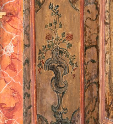 Zdjęcie nr 16: Umeblowanie zakrystii usytuowane jest wzdłuż ścian północnej, południowej i wschodniej pomieszczenia.  Na ścianie północnej, w części dolnej znajdują się trzy połączone ze sobą komody, każda o czterech szufladach, nakryte jednym blatem. W części górnej mieszczą się pięcioosiowe szafki z szufladami w cokole. Osie artykułowe są pilastrami hermowymi. Na osi środkowej szafka jest nieco wyższa i szersza z drzwiczkami dekorowanymi prostokątną, uszatą, oprofilowaną płyciną z malowanym przedstawieniem Chrystusa Eucharystycznego. Drzwiczki pozostałych szafek mają kształt stojących prostokątów i dekorowane są płycinami o wklęsłych narożach, zdobionymi gałązkami czerwonych róż, ułożonych w rokokowych wazonach. Ścianki zamknięte są niepełnym belkowaniem z gzymsem. W partii zwieńczenia osie artykułowane są cokolikami, na których ustawione są toczone, kuliste wazoniki. Pomiędzy nimi umieszczone są kartusze utworzone z ornamentu małżowinowo-chrząstkowego z malowanymi emblematami na owalnych medalionach, które ułożone są kolejno od lewej strony: 
1. Pionowo ustawiony miecz, ostrzem skierowany ku górze, połączony ze skrzyżowanymi berłem i dwoma kluczami, od których odchodzą fantazyjnie ułożone sznury w kolorze czerwonym. U góry napis na szarfie: „OBEDITE”.
2. W górnej części wyłaniająca się z chmur ręka trzymająca w dłoni węgielnicę i przymocowane do niej na łańcuszku tablice Dekalogu. Napis na szarfie: „OMNIA SVSTINET”.
3. Bóg Ojciec ukazany w półpostaci, lewą ręką opiera się na kuli ziemskiej, prawą czyni gest błogosławieństwa. 
4. Bujnie ulistnione, ciemnozielone drzewko spięte w dolnej części złotą formą w kształcie dwóch wywiniętych wolutek. Napis na szarfie: „GAVDET PATIENTIA DVRIS”. 
5. W górnej części obrazu z chmur wyłania się ręka, która zrzuca na ziemię iskrzący pocisk i dwa skrzyżowane pioruny, połączone parą białych skrzydeł. Napis „FORTIS VLTOR”.
 
Na ścianie środkowej, wschodniej znajduje się sarkofagowa mensa, powyżej parawanowa ścianka na profilowanym cokole, artykułowana pilastrami, pomiędzy którymi umieszczone są płyciny z kształcie leżących prostokątów z obrazami; ścianka zamknięta jest profilowanym gzymsem. W zwieńczeniu, na jej skrajach znajdują się owalne medaliony ujęte w kartusze z ornamentu małżowinowo-chrząstkowego. W medalionie po lewej stronie namalowane są litery alfa i omega na błękitnym tle oraz wstęga z napisem: „RENOVATUM A(NNO) D(OMINI) 1975”. Po prawej stronie analogiczny kartusz z literami w medalionie: „Ω / O / N” wpisane w formę krzyża, otoczonego niepełną aureolą; powyżej wstęga z napisem: „VIDENTEM AUDERE”. W płycinach obrazy przedstawiają świętych w ujęciu do pasa, zwróconych ku środkowi; od lewej:
1. Święty Demetriusz z włócznią opartą o prawy bark, ubrany w habit zakonu kanoników laterańskich od pokuty.
2. Święty Klet z aniołkiem, który trzyma w dłoni palmę męczeństwa i krzyż papieski. W prawym górnym narożu obrazu napis: „FAC HVIC SIGNO HONOREM”.
3. Święty Augustyn z gorejącym sercem na piersi i aniołkiem z łyżką i miseczką w dłoniach.
4. Święty ubrany w habit Marków, który trzyma w dłoni serce z krzyżem, podtrzymywane przez Chrystusa na obłokach – prawdopodobnie św. Cyriak, założyciel zakonu.
 
Na ścianie południowej znajduje się analogiczne umeblowanie, jak na ścianie północnej. W dolnej części dwie komody, a w miejscu trzeciej od wschodu szafka zdobiona dwiema uszatymi płycinami. Górna część mebla w przeciwieństwie do ściany północnej bez podwyższenia części środkowej. 
Na ścianie południowej:
1. Jasnobrązowa harfa na błękitnym tle i napis: „IN DOMINO”.
2. Ciemnobrązowy ptak i trzy podrywające się do lotu młode, w górnej części złote słońce i napis: „NON QUAE SVPER TERRAM.”
3. Po lewej stronie kompozycji wyłaniająca się z chmur ręka trzymająca skrzyżowane: miecz, czerwony krzyż i palmę. Napis: „NON ERVBESCO”.
4. W centrum przedstawienia krzak białej lilii o trzech rozgałęzieniach, w tle chmury w odcieniach koloru szaroniebieskiego. Napis na szarfie: „PER ARDVA DVLCIS”.
5. W lewej części kompozycji uskrzydlony jeleń, wspięty na tylnych nogach, po prawej stronie czarne i brązowe skały, w partii górnej otwarta korona, umieszczona pośrodku obłoku obwiedzionego biało-czerwonym pasem. Napis: „ET COMPREHENDATIS”.
 
W miejscu połączenia komód ścian północnej i południowej z dolną częścią konstrukcji na ścianie wschodniej znajdują się ukośnie ustawione, jednoskrzydłowe szafki o drzwiczkach dekorowanych prostokątną płyciną o wklęsłych narożach. Ścianki boczne części północnej i południowej zdobione są ukośną kratką. Powierzchnia szafek i komód pokryta jest polichromią imitującą marmur w kolorze beżowym, szarokremowym, różowym i rdzawym. Blaty malowane są farbą olejną w kolorze beżowym. Obramienia medalionów malowane w kolorze rdzawozłotym. Tło w większości medalionów w odcieniach błękitu, w górnych częściach majuskułowe napisy objaśniające przedstawienie, umieszczone w białych i półkoliście ułożonych szarfach. 