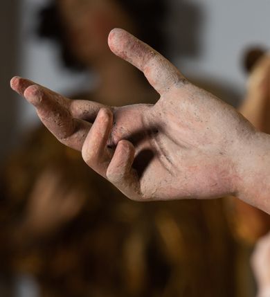 Zdjęcie nr 6: Rzeźba pełnoplastyczna, ścięta i drążona od tyłu.
Postać anioła o charakterystycznym wydłużeniu sylwetki, esowato wygięta i ustawiona na postumencie w lekkim kontrapoście;  ciężar ciała postaci wsparty na lewej nodze, lewa ręka zagięta w łokciu na wysokości pasa, prawa ręka podtrzymuje wydłużony kartusz. Nogi okryte są złotą draperią, która tworzy ekspresyjne, sztywne i lekko rozwiane fałdy. Opadająca z prawego ramienia szata obnaża goły tors i podbrzusze opadając na biodra. Drobna twarz skierowana jest na wprost, usta są pełne, lekko rozchylone, a pukle włosów opadają swobodnie na ramiona. Skrzydła są szeroko rozpostarte.