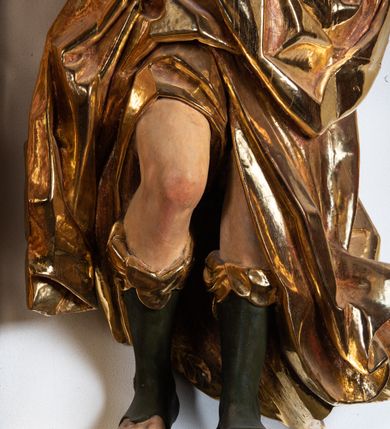 Zdjęcie nr 4: Rzeźba niemal pełnoplastyczna, ścięta. Stoi na konsoli małżowinowo chrząstkowej w lekkim kontrapoście z ciężarem ciała opartym na lewej nodze, ukazana jest frontalnie z wysuniętymi do przodu rękami ugiętymi w łokciach na wysokości pasa i głową przechyloną w prawo. Owalna, wydłużona twarz o pełnych policzkach, długim nosie, wąskich ustach i szeroko otwartych oczach, włosy krótkie faliste, rozwiane, zakrywające uszy. Rzeźba ubrana jest w tunikę z podwiniętymi rękawami, przepasaną na biodrze, odsłaniającą prawe udo i część lewej łydki oraz zarzucony na lewe ramię płaszcz z połą zarzuconą na prawe udo. Szaty modelowane ostrymi krawędziami, z podwiniętą dolną częścią płaszcza.