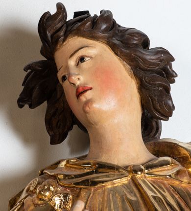 Zdjęcie nr 5: Rzeźba niemal pełnoplastyczna, ścięta. Stoi na konsoli małżowinowo chrząstkowej w lekkim kontrapoście z ciężarem ciała opartym na lewej nodze, ukazana jest frontalnie z wysuniętymi do przodu rękami ugiętymi w łokciach na wysokości pasa i głową przechyloną w prawo. Owalna, wydłużona twarz o pełnych policzkach, długim nosie, wąskich ustach i szeroko otwartych oczach, włosy krótkie faliste, rozwiane, zakrywające uszy. Rzeźba ubrana jest w tunikę z podwiniętymi rękawami, przepasaną na biodrze, odsłaniającą prawe udo i część lewej łydki oraz zarzucony na lewe ramię płaszcz z połą zarzuconą na prawe udo. Szaty modelowane ostrymi krawędziami, z podwiniętą dolną częścią płaszcza.