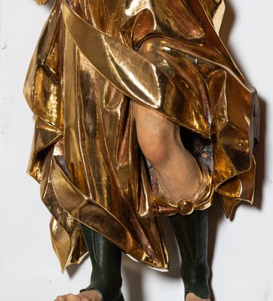 Zdjęcie nr 5: Forma niemal pełnoplastyczna i ścięta. Rzeźba stoi na konsoli małżowinowo chrząstkowej w lekkim kontrapoście z ciężarem ciała opartym na prawej nodze, ukazana jest frontalnie z wysuniętymi do przodu rękami, prawa uniesiona na wysokości głowy i znacznie odsunięta od tułowia, lewa lekko ugięta w łokciu na wysokości pasa.  Głowa przechylona w lewo. Okrągła twarz o pełnych policzkach i małym podbródku, długim nosie, wąskich, drobnych ustach i  szeroko otwartych oczach, włosy krótkie faliste, rozwiane, nieznacznie odkrywające uszy. Rzeźba ubrana jest w tunikę z podwiniętymi rękawami, przepasaną na biodrze, odsłaniającą lewe udo oraz w zarzucony na lewe ramię płaszcz z połą zarzuconą na prawe udo. Szaty modelowane ostrymi krawędziami, z podwiniętą dolną częścią płaszcza.