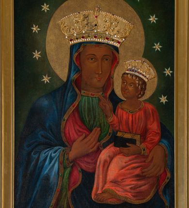 Zdjęcie nr 2: Obraz uzyskał kształt stojącego prostokąta ujętego w proste, złocone i profilowane ramy oraz dekoracyjne obramienie utworzone z płaskorzeźbionego ornamentu małżowinowo-chrząstkowego przytwierdzonego do zielono-błękitnego marmurowego tła. W zwieńczeniu obramienia kartusz z napisem: AVE MARIA. W centrum kompozycji na ciemnym, jednolitym tle ukazano frontalnie Madonnę z Dzieciątkiem w typie Matki Boskiej Częstochowskiej. Maria na lewym przedramieniu trzyma Dzieciątko Jezus, na które wskazuje prawą ręką przyłożoną do piersi. Matka Boska ma pociągłą twarz o brązowej karnacji z wyraźnie zaznaczonymi drobnymi ustami o pełnych wargach, wydatnym nosie i małych, migdałowych, otwartych oczach. Na jej prawym policzku widoczne są dwie rysy. Madonna ubrana jest w ciemnoniebieski maforion podbity czerwienią i lamowany taśmą z malarskim naśladownictwem kameryzacji. Spod maforionu widoczna jest zielona, marszczona suknia obwiedziona pod szyją taśmą także z malarskim naśladownictwem kameryzacji. Siedzące Dzieciątko Jezus zostało ujęte w trzech czwartych w prawo. Prawą rękę unosi w geście błogosławieństwa, lewą zaś podtrzymuje na kolanach zamknięty na dwie klamry kodeks. Jezus o jasnobrązowej karnacji ma owalną twarz o spojrzeniu skierowanym na matkę, mały nos i pełne usta. Jego głowę otaczają kędzierzawe, brązowe włosy rozjaśnione przy końcówkach loków. Ubrany jest w czerwoną, marszczoną na piersi tunikę lamowaną pod szyją, u spodu i przy rękawach taśmą z malarskim naśladownictwem kameryzacji. Spod tuniki wdać na dole jego bosą stopę. Głowy obu postaci otaczają złocone nimby oraz dwanaście malowanych gwiazd, na które nałożono mniejsze, metalowe i złocone. Na głowach Marii i Jezusa nałożone są srebrne i złocone korony o floranych sterczynach zdobione kameryzacją.    
