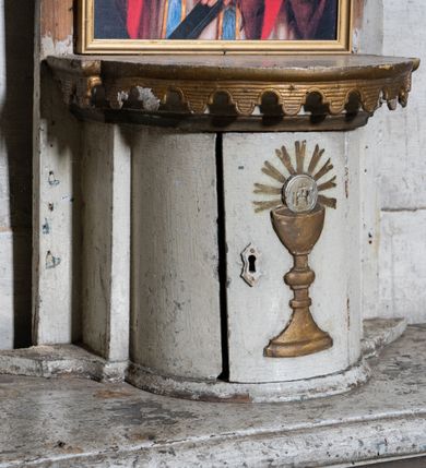 Zdjęcie nr 12: Przyścienny ołtarz Matki Boskiej Częstochowskiej uzyskał formę architektonicznej nastawy jednokondygnacyjnej, jednoosiowej ze zwieńczeniem. Drewniana mensa z portatylem flankowana przez dwustrefowy wklęsło-wypukły cokół wspiera się na ażurowym, konsolowym stipesie ołtarzowym, dekorowanym ornamentami rocalliowymi. Kondygnacja wsparta na dwustrefowym cokole została ujęta dwiema parami pilastrów zwróconych delikatnie do wewnątrz oraz silnie wysuniętą do przodu parą kolumn o kapitelach kompozytowych. Podpory dźwigają belkowanie o wklęsło-wypukłej linii. Nad polem środkowym belkowanie jest przerwane, a na osiach podpór wyłamane. Na przedłużeniu kolumn na belkowaniu usytuowano wolutowe przyczółki dekorowane rocalliem, stanowiących postumenty do skradzionych figur aniołów. W polu środkowym umieszczono obecnie obraz Matki Boskiej Nieustającej Pomocy Najświętszego, ujęty profilowaną, złoconą ramą w formie stojącego prostokąta zamkniętego łukiem półkolistym nadwieszonym z uskokiem, dekorowaną ornamentem rocalliowym. Poniżej obrazu pomiędzy dwiema rocalliowymi konsolami widnieje zdjęcie obrazu św. Jana Nepomucena. Zwieńczenie uzyskało formę leżącego prostokąta o wklęsłych, wolutowych bokach przechodzących u góry we wklęsło-wypukłe belkowanie, przyjmujące nad polem formę łuku falistego. W polu zwieńczenia znalazło się zdjęcie obrazu ze św. Józefem ujęte we wklęsło-wypukłą, profilowaną i złoconą ramę. Pilastry kondygnacji ozdobiono kapitelami z rocaille, a ich trzony udekorowano złoconymi zwisami utworzonymi z rocaille, rozet i liści. Całość struktury polichromowano na biało, a ornamenty i profile zostały wyzłocone. 