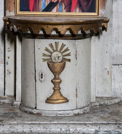 Zdjęcie nr 11: Przyścienny ołtarz Matki Boskiej Częstochowskiej uzyskał formę architektonicznej nastawy jednokondygnacyjnej, jednoosiowej ze zwieńczeniem. Drewniana mensa z portatylem flankowana przez dwustrefowy wklęsło-wypukły cokół wspiera się na ażurowym, konsolowym stipesie ołtarzowym, dekorowanym ornamentami rocalliowymi. Kondygnacja wsparta na dwustrefowym cokole została ujęta dwiema parami pilastrów zwróconych delikatnie do wewnątrz oraz silnie wysuniętą do przodu parą kolumn o kapitelach kompozytowych. Podpory dźwigają belkowanie o wklęsło-wypukłej linii. Nad polem środkowym belkowanie jest przerwane, a na osiach podpór wyłamane. Na przedłużeniu kolumn na belkowaniu usytuowano wolutowe przyczółki dekorowane rocalliem, stanowiących postumenty do skradzionych figur aniołów. W polu środkowym umieszczono obecnie obraz Matki Boskiej Nieustającej Pomocy Najświętszego, ujęty profilowaną, złoconą ramą w formie stojącego prostokąta zamkniętego łukiem półkolistym nadwieszonym z uskokiem, dekorowaną ornamentem rocalliowym. Poniżej obrazu pomiędzy dwiema rocalliowymi konsolami widnieje zdjęcie obrazu św. Jana Nepomucena. Zwieńczenie uzyskało formę leżącego prostokąta o wklęsłych, wolutowych bokach przechodzących u góry we wklęsło-wypukłe belkowanie, przyjmujące nad polem formę łuku falistego. W polu zwieńczenia znalazło się zdjęcie obrazu ze św. Józefem ujęte we wklęsło-wypukłą, profilowaną i złoconą ramę. Pilastry kondygnacji ozdobiono kapitelami z rocaille, a ich trzony udekorowano złoconymi zwisami utworzonymi z rocaille, rozet i liści. Całość struktury polichromowano na biało, a ornamenty i profile zostały wyzłocone. 