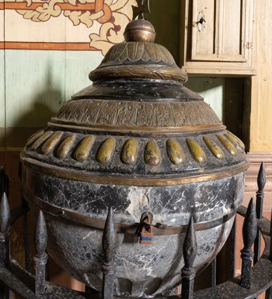 Zdjęcie nr 2: Chrzcielnica osadzona na cylindrycznej, wysokiej podstawie, ze stopą na rzucie koła, z cokolikiem i płaszczem płynnie przechodzącym w okrągły trzon. Trzon przedzielony kostkowym nodusem, zwieńczony opaską. Czara od dołu zdobiona obłymi rowkami zwieńczona szerokim kołnierzem. Pokrywa trójstrefowa, dołem puklowana, w środkowej części zdobiona pasem z liści, w górnej zakończona odwróconym talerzykiem z wieńcem laurowym i od górypokrytym palmetkami. Pokrywę wieńczy kula z krzyżem. 