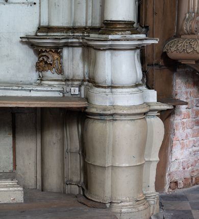 Zdjęcie nr 13: Przyścienny ołtarz Najświętszego Serca Pana Jezusa uzyskał formę architektonicznej nastawy jednokondygnacyjnej, jednoosiowej ze zwieńczeniem. Drewniana mensa z portatylem flankowana przez dwustrefowy wklęsło-wypukły cokół retabulum pierwotnie wspierała się na ażurowym, konsolowym stipesie ołtarzowym, dekorowanym ornamentami rocalliowymi. Kondygnacja wsparta na dwustrefowym cokole została ujęta dwiema parami pilastrów zwróconych delikatnie do wewnątrz oraz silnie wysuniętą do przodu parą kolumn o kapitelach kompozytowych. Podpory dźwigają belkowanie o wklęsło-wypukłej linii. Nad polem środkowym belkowanie jest przerwane, a na osiach podpór wyłamane. Na przedłużeniu kolumn na belkowaniu usytuowano wolutowe przyczółki dekorowane rocalliem, stanowiących postumenty do skradzionych figur aniołów. W polu środkowym umieszczono obraz Najświętszego Serca Pana Jezusa, ujęty profilowaną, złoconą ramą w formie stojącego prostokąta zamkniętego łukiem półkolistym nadwieszonym z uskokiem. Poniżej obrazu pomiędzy dwiema rocalliowymi konsolami widnieje zdjęcie obrazu św. Katarzyny Aleksandryjskiej. Zwieńczenie uzyskało formę leżącego prostokąta o wklęsłych, wolutowych bokach przechodzących u góry we wklęsło-wypukłe belkowanie, przyjmujące nad polem formę łuku falistego. W polu zwieńczenia znalazło się zdjęcie obrazu ze św. Sebastianem ujęte we wklęsło-wypukłą, profilowaną i złoconą ramę. Na szczycie w rocalliowym kartuszu wyobrażono złocony chrystogram "IHS" w srebrnym polu. Pilastry kondygnacji ozdobiono kapitelami z rocaille, a ich trzony udekorowano złoconymi zwisami utworzonymi z rocaille, rozet i liści. Całość struktury polichromowano na biało, a ornamenty i profile zostały wyzłocone. 